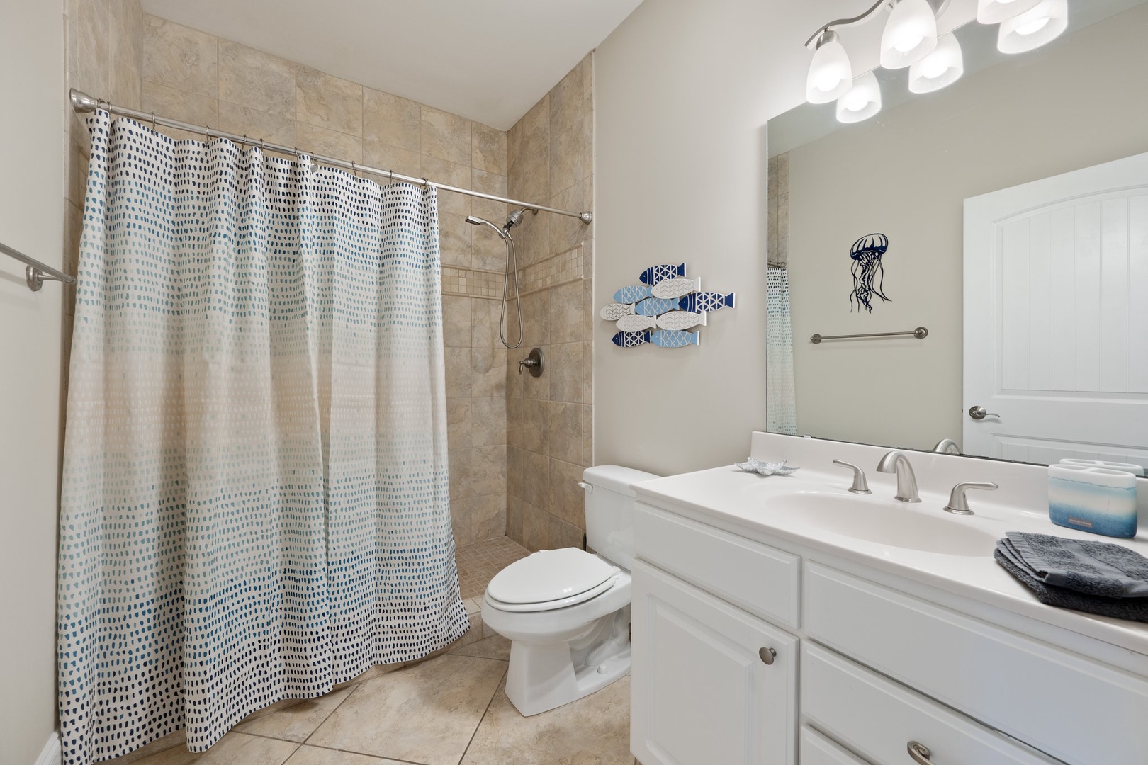 Refresh in your coastal-themed bathroom featuring a spacious shower, beautiful tile work, and charming sea life decor that adds a peaceful touch.