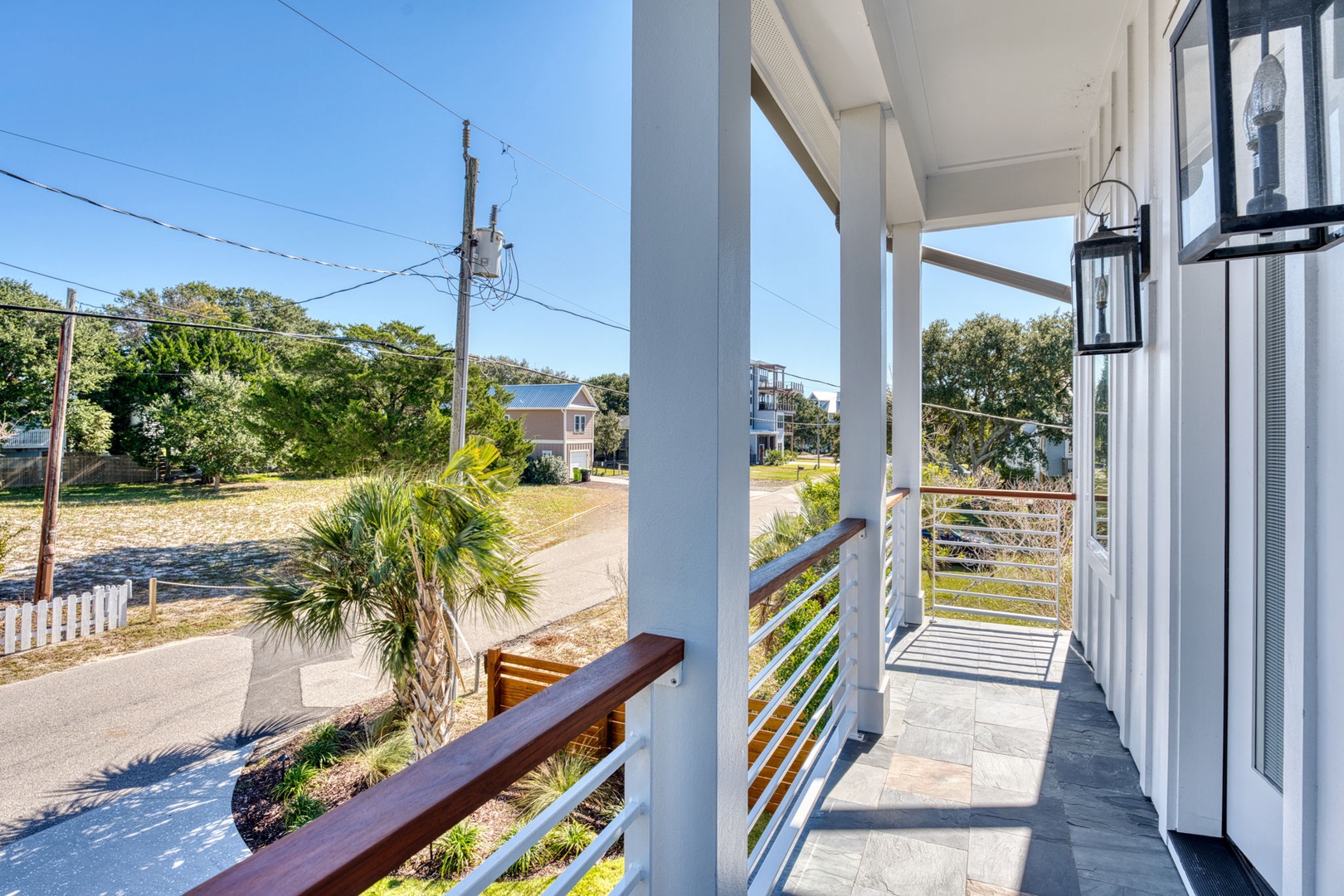 Modern covered porch with sleek railings showcasing the peaceful coastal neighborhood surroundings.