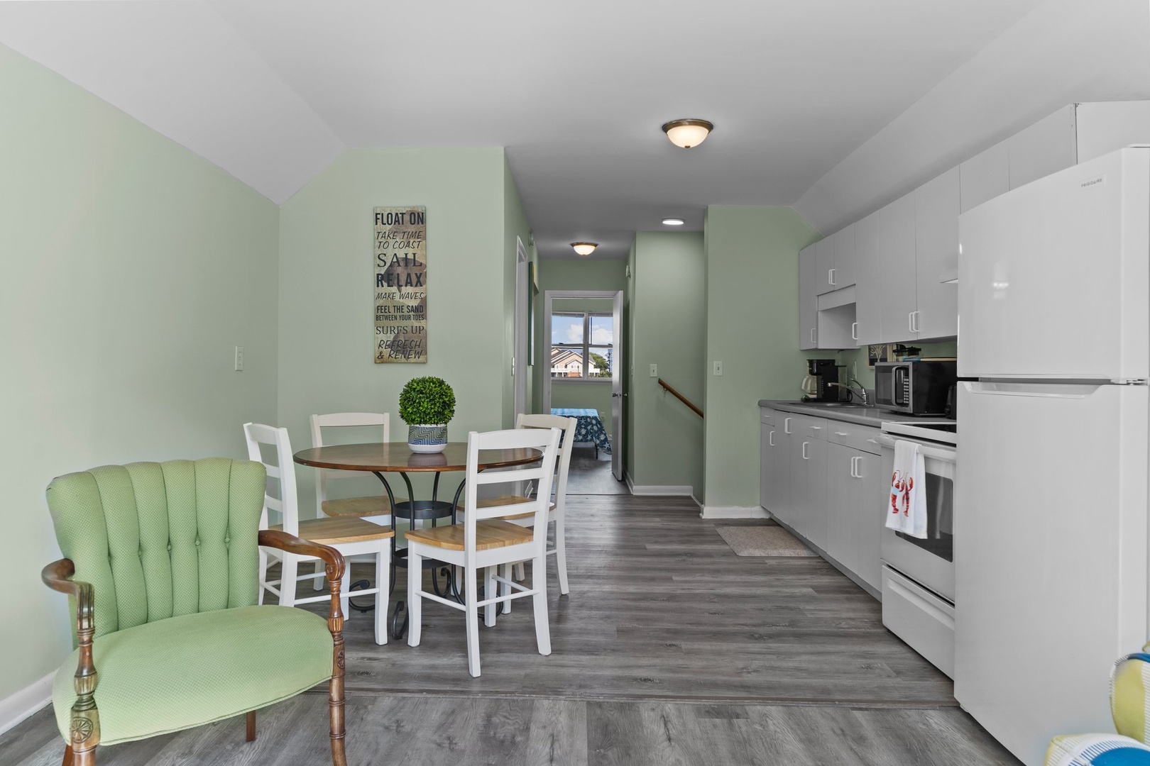 Your open kitchen and dining area invites leisurely meals with calming green walls and modern appliances at your fingertips.