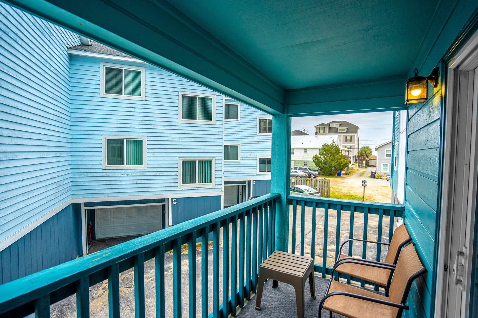 Relax on your private turquoise balcony with comfortable seating and peaceful neighborhood views.