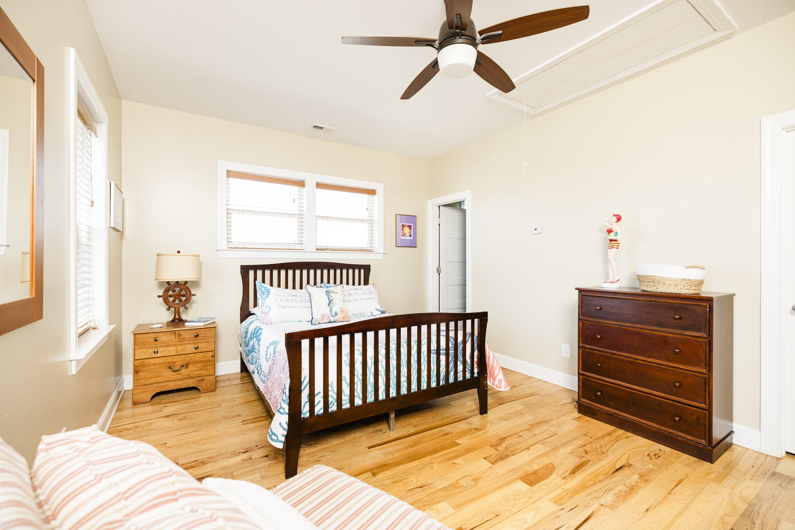 Your peaceful bedroom features warm wood floors, coastal bedding, and a ceiling fan for comfort.