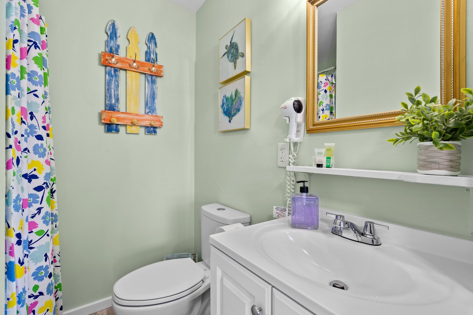 Refresh in your charming bathroom featuring coastal artwork, thoughtful amenities, and cheerful floral accents that create a welcoming retreat.