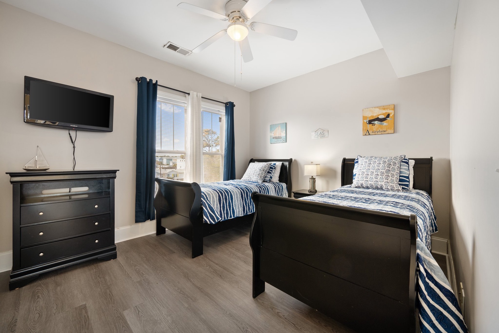Rest comfortably in this twin bedroom with nautical charm, featuring two cozy beds, ceiling fan, and TV for relaxing evenings.