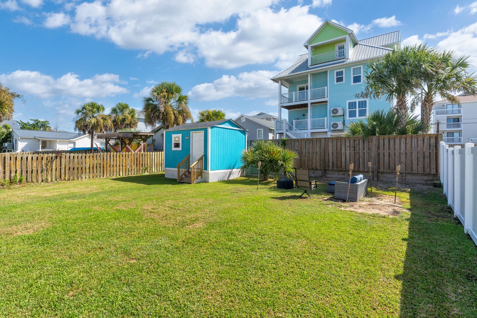 Coastal property features a spacious grassy yard with colorful beach house architecture and tropical palm trees.