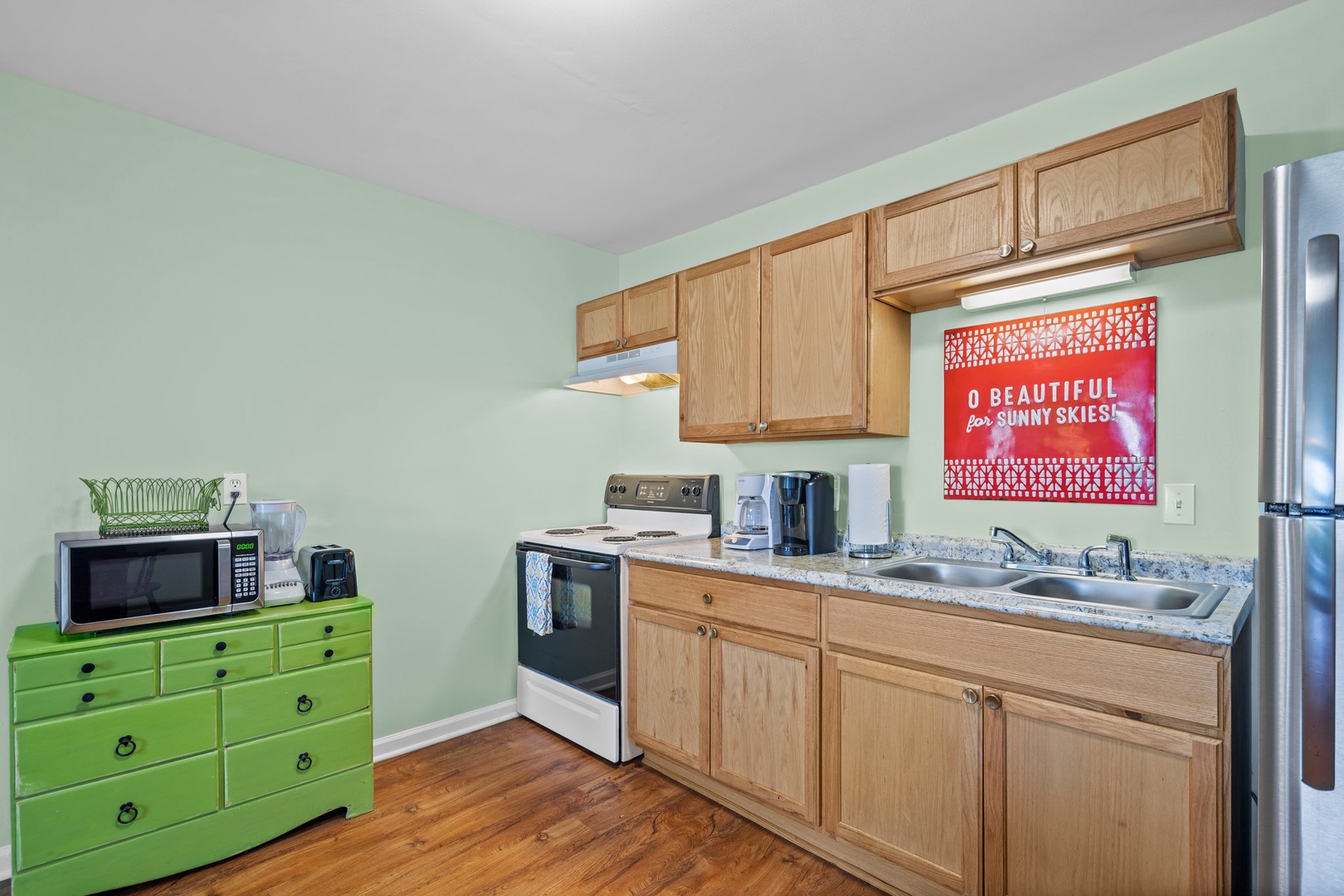 Your bright kitchen features warm wood cabinets, full appliances, and cheerful green accents—perfect for preparing meals during your stay.