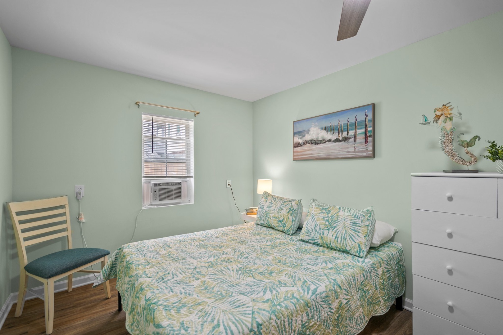 Drift into peaceful dreams in your coastal-themed bedroom, where soft mint walls and tropical bedding create your perfect seaside sanctuary.