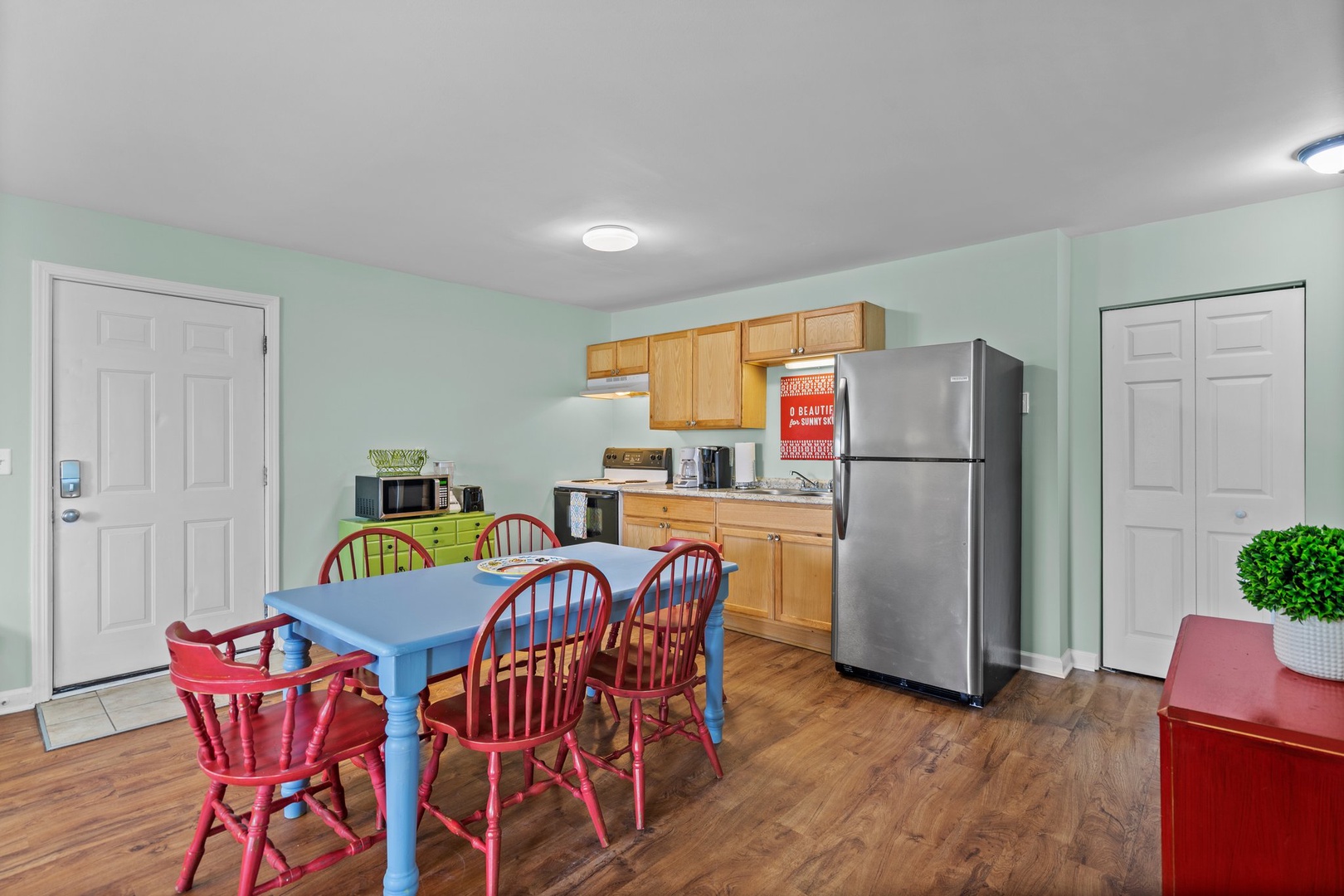 Your cheerful kitchen and dining space features colorful red chairs around a blue table, perfect for family meals and morning coffee.