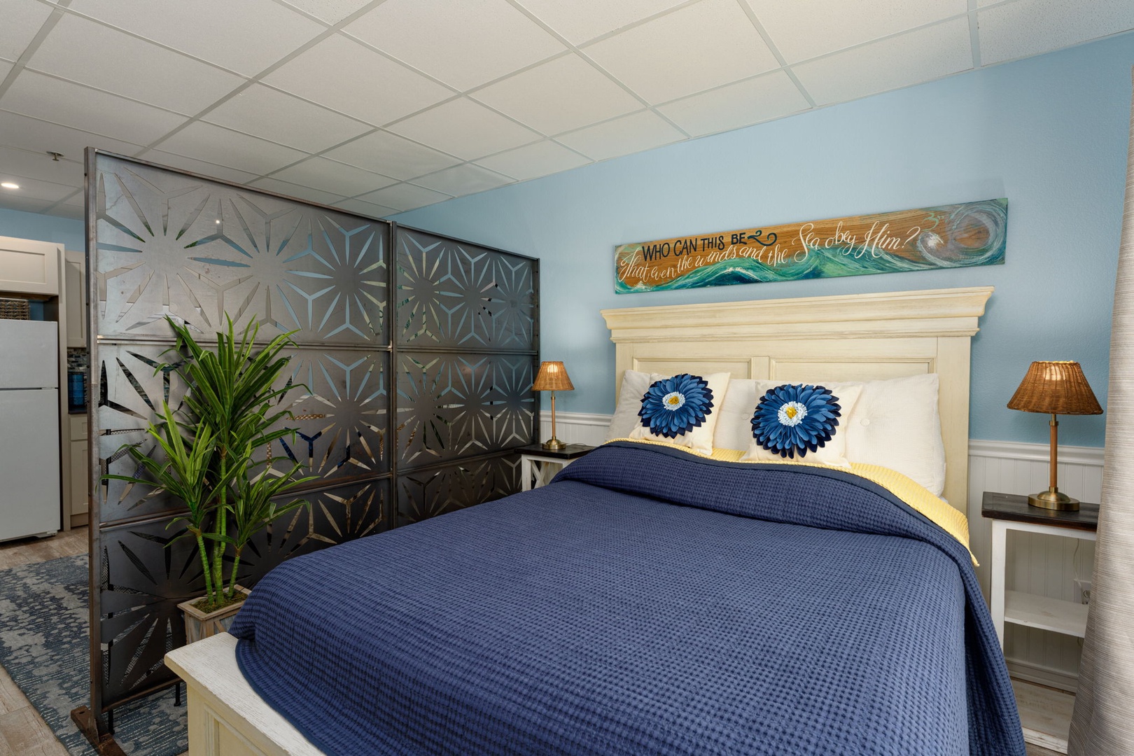 Drift off in your coastal-themed bedroom featuring navy bedding, decorative screens, and ocean-inspired artwork for peaceful sleep.