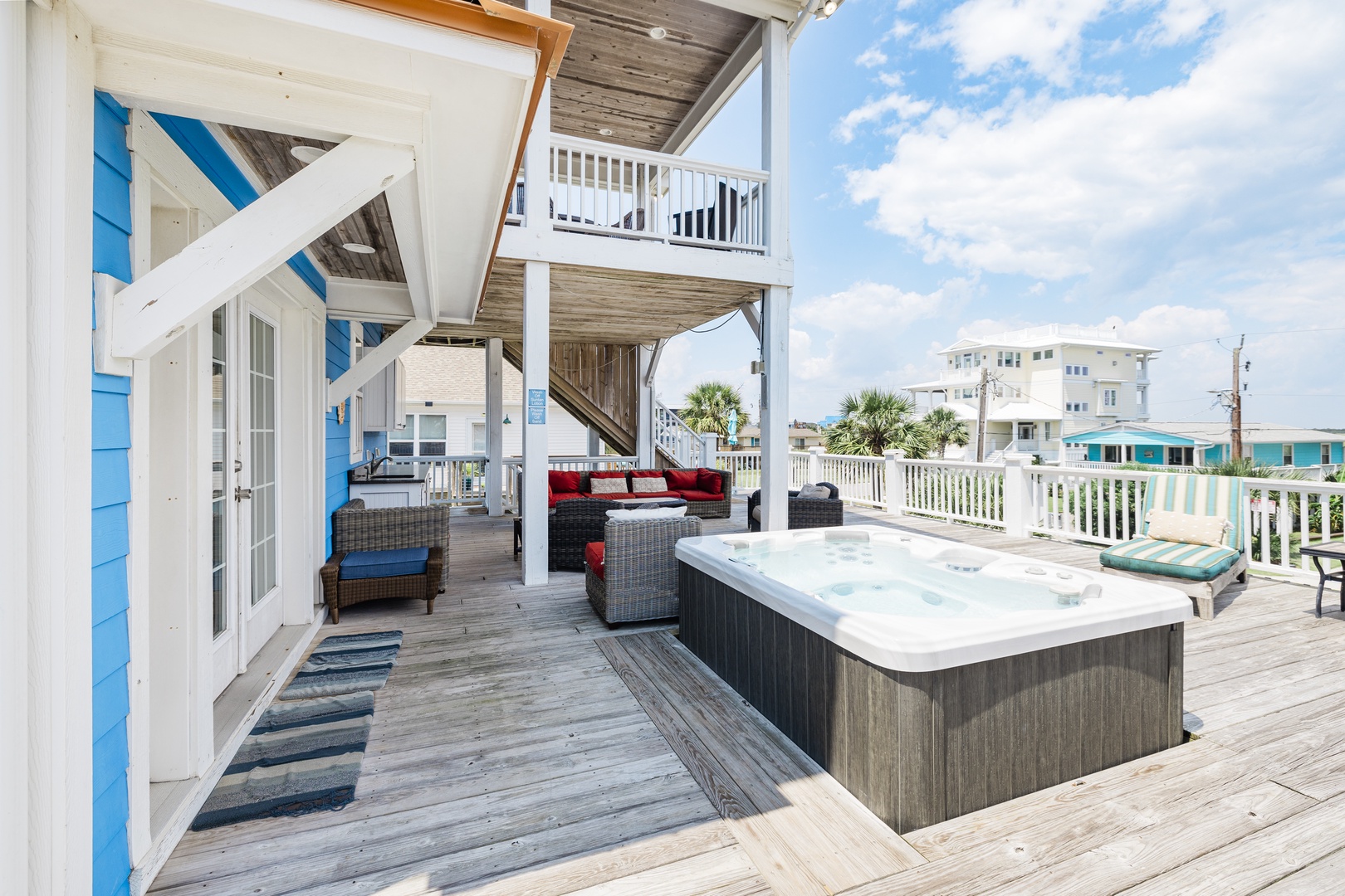 Soak in your private hot tub while enjoying ocean breezes on this expansive deck with lounge seating and coastal charm.