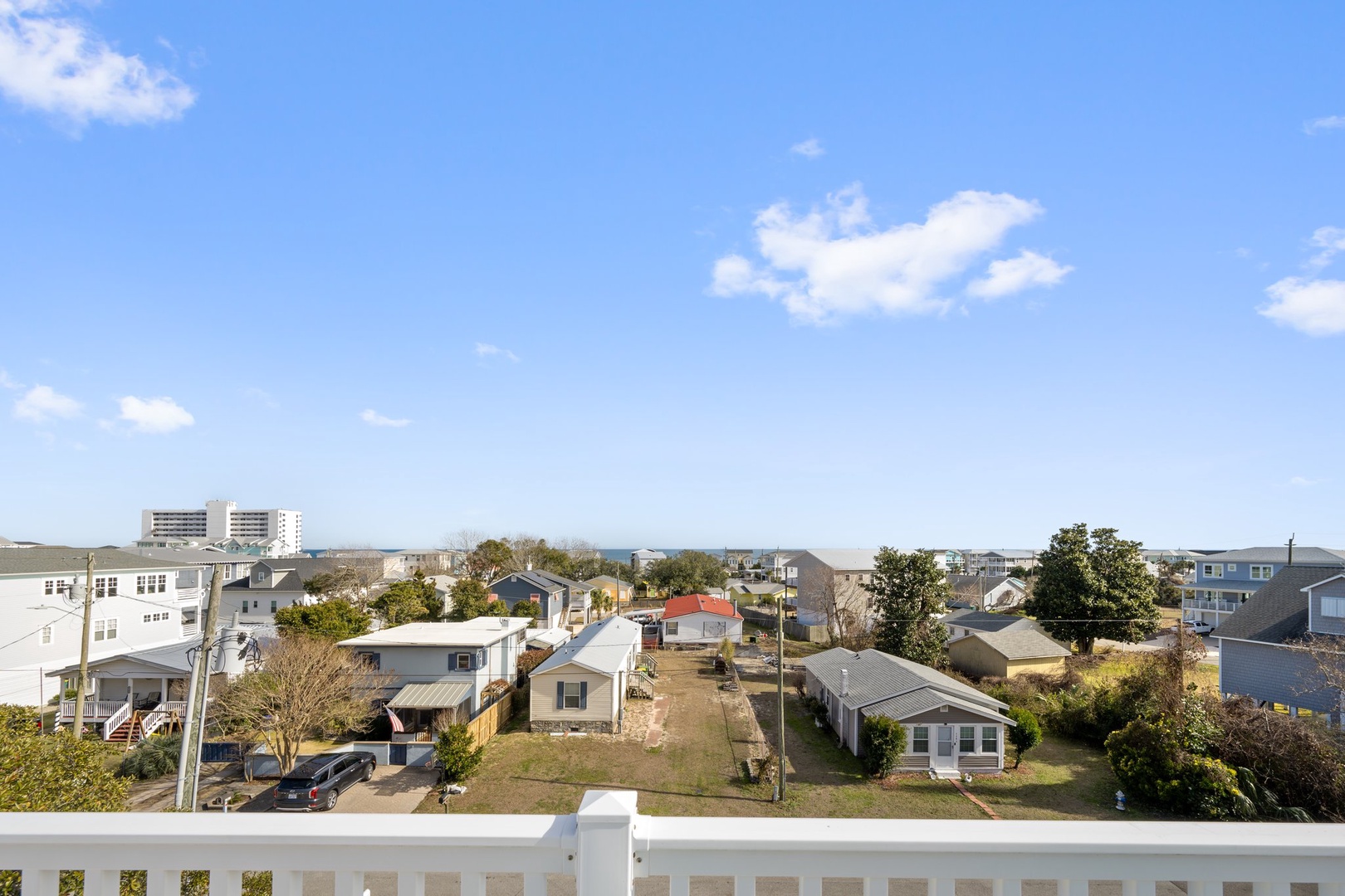 Elevated view showcasing the residential neighborhood surrounding the property, with a mix of homes and nearby buildings under clear blue skies.