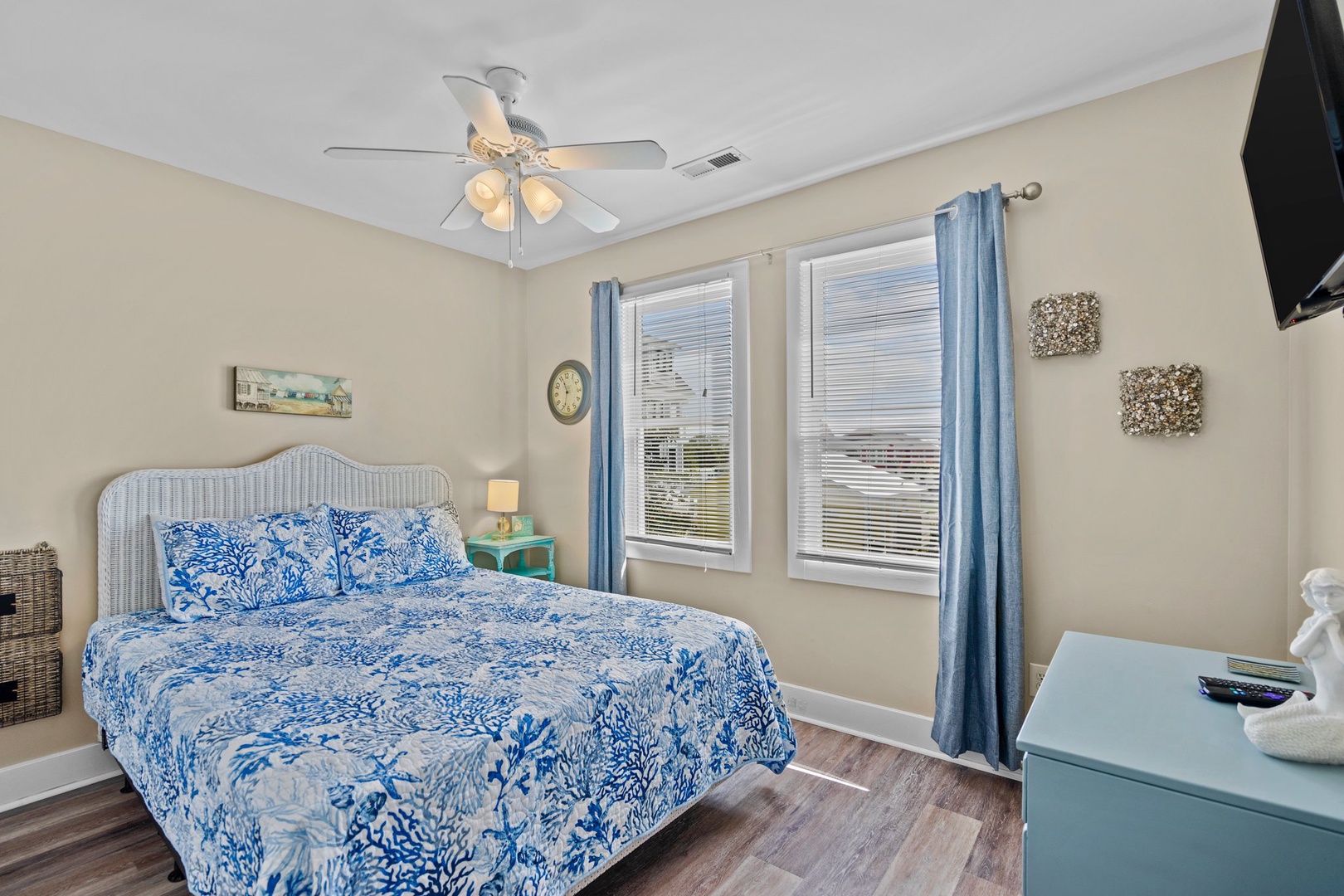 Drift off in your coastal-themed bedroom featuring blue coral bedding, gentle ceiling fan breeze, and morning light through the windows.