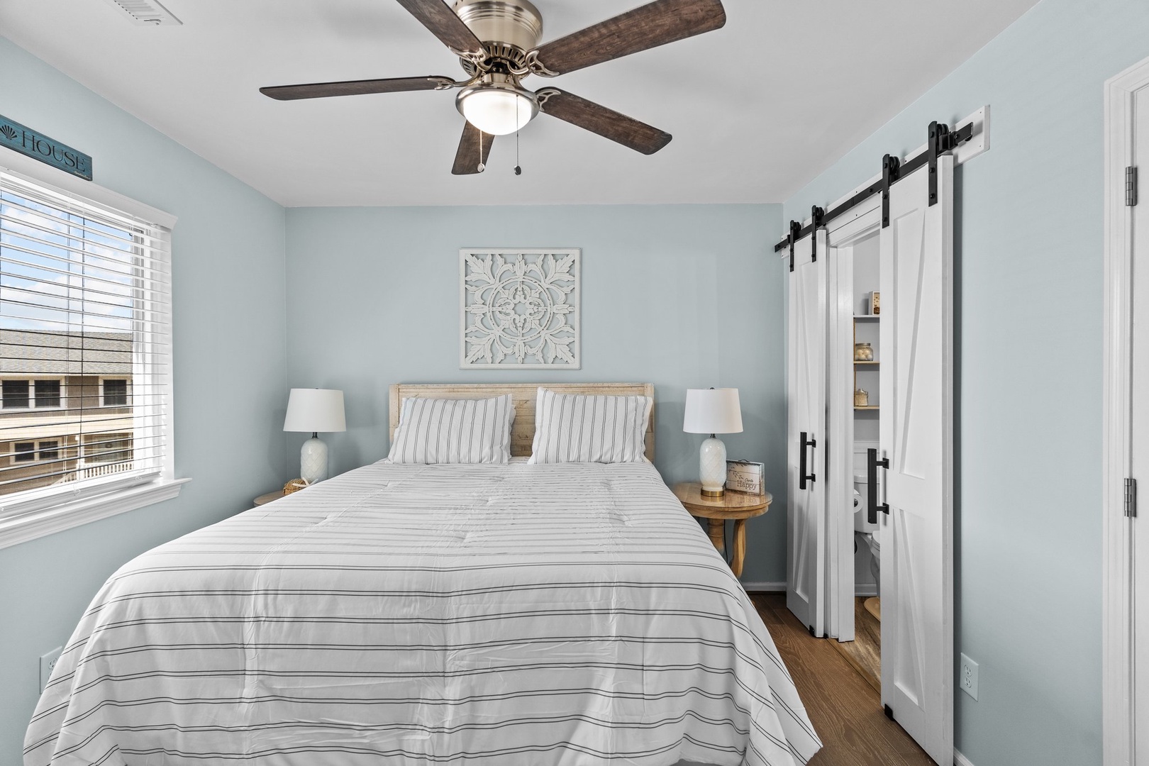 Drift off in this peaceful bedroom with soft linens, calming coastal colors, and a ceiling fan for comfort.