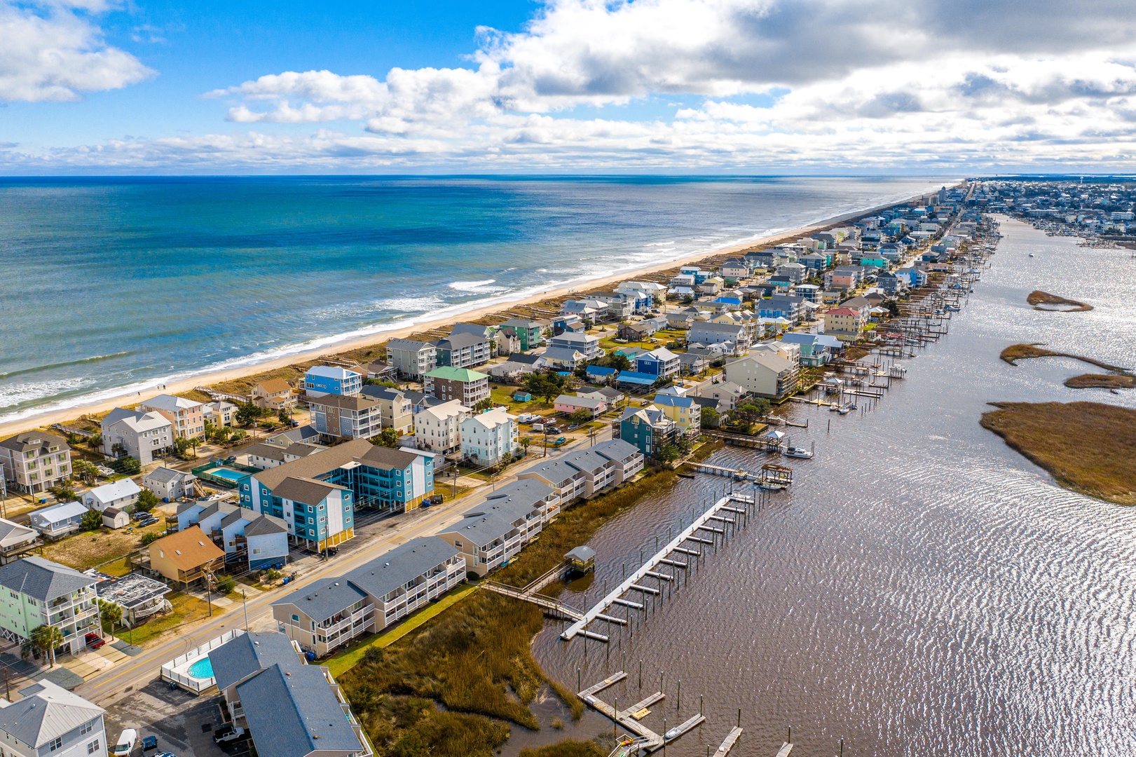 Spectacular aerial view of a coastal community featuring pristine beaches, waterfront homes, and marina access along the scenic shoreline.