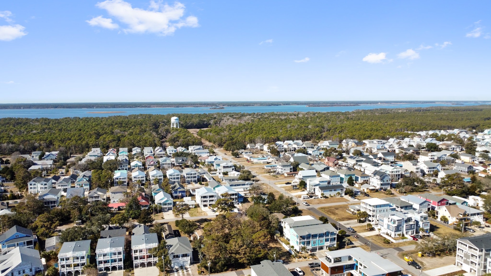 Aerial view of the coastal community showing waterfront homes nestled among trees near pristine waters.