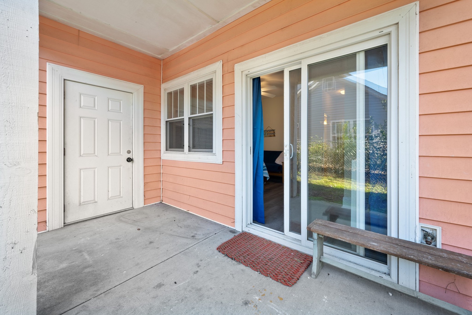 Step onto your private patio, where sliding doors welcome you into your coastal retreat with warm coral siding and peaceful views.