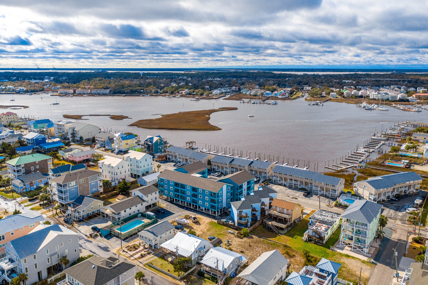 Aerial view of a vibrant coastal community featuring colorful buildings, marina access, and scenic waterfront surroundings.