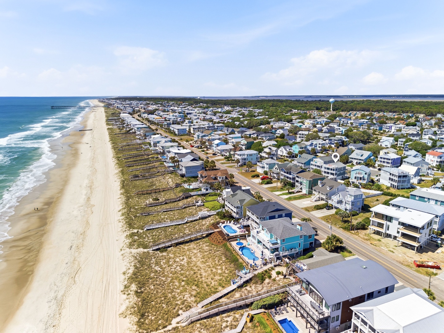 Aerial view of a beachfront vacation community featuring sandy shores, residential properties, and coastal development stretching along the shoreline.