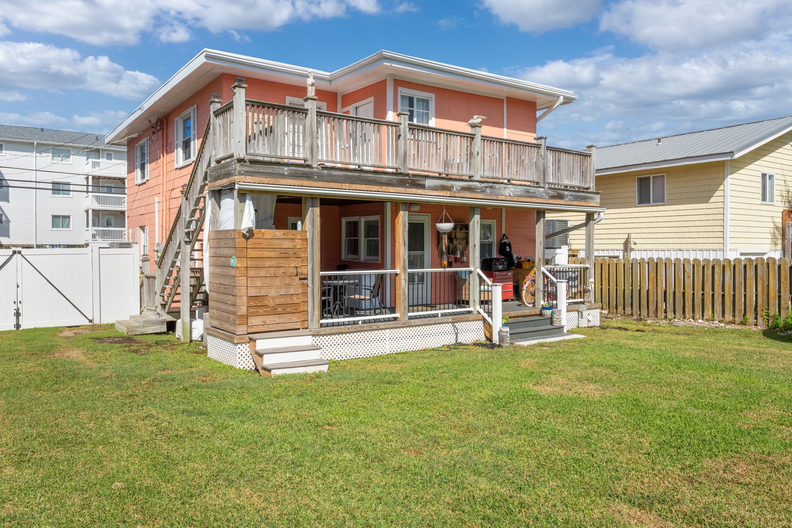 A charming coral-colored beach house with spacious balcony and outdoor shower, nestled in a quiet residential neighborhood.