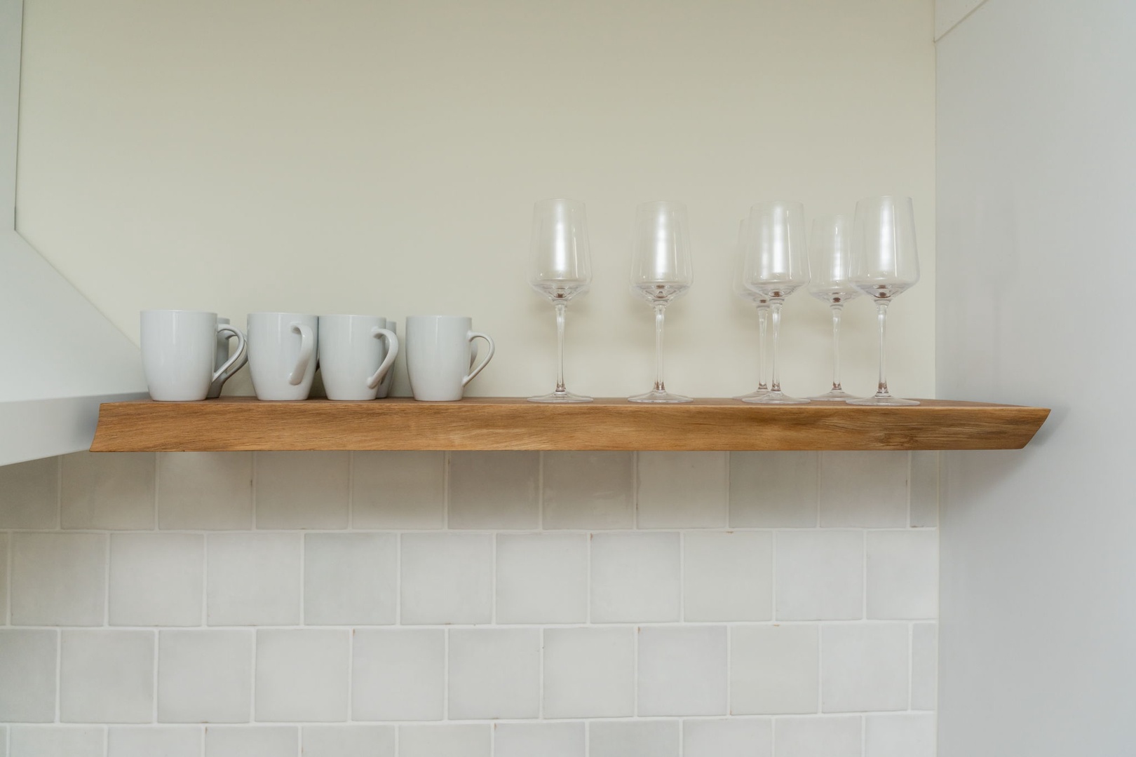 Your kitchen comes thoughtfully equipped with elegant glassware and coffee cups on a warm wooden shelf, perfect for morning coffees or evening wine.