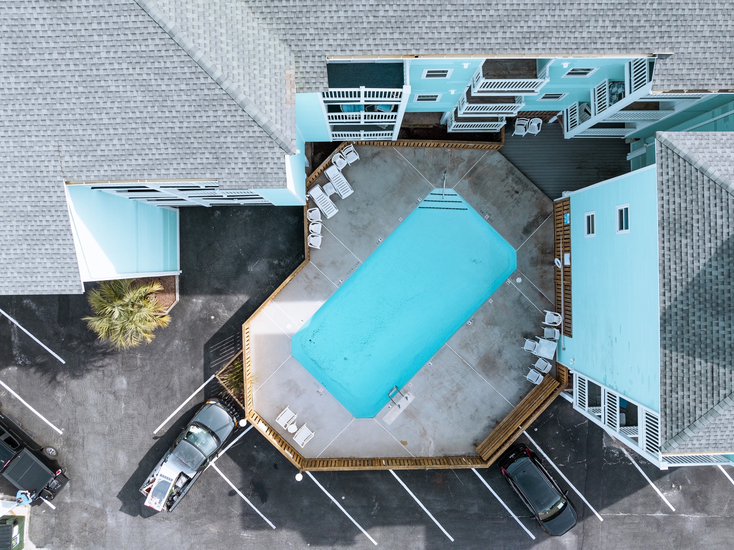 Aerial view of property featuring a sparkling swimming pool surrounded by modern buildings and convenient parking.