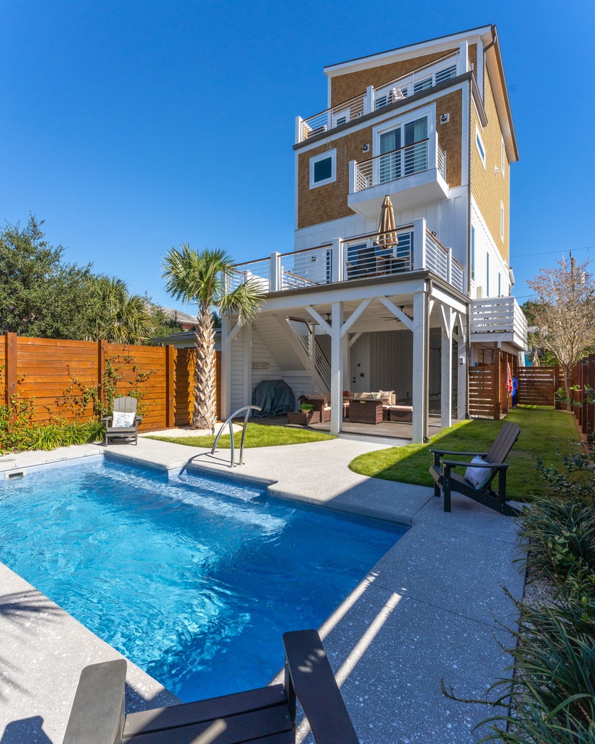 Modern multi-story vacation rental featuring a private swimming pool and covered outdoor living space with tropical landscaping.