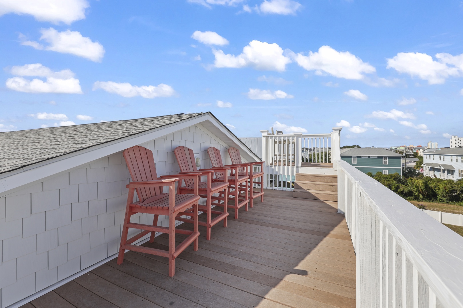 Rooftop deck with Adirondack-style seating offering panoramic views of the surrounding coastal neighborhood and nearby buildings.