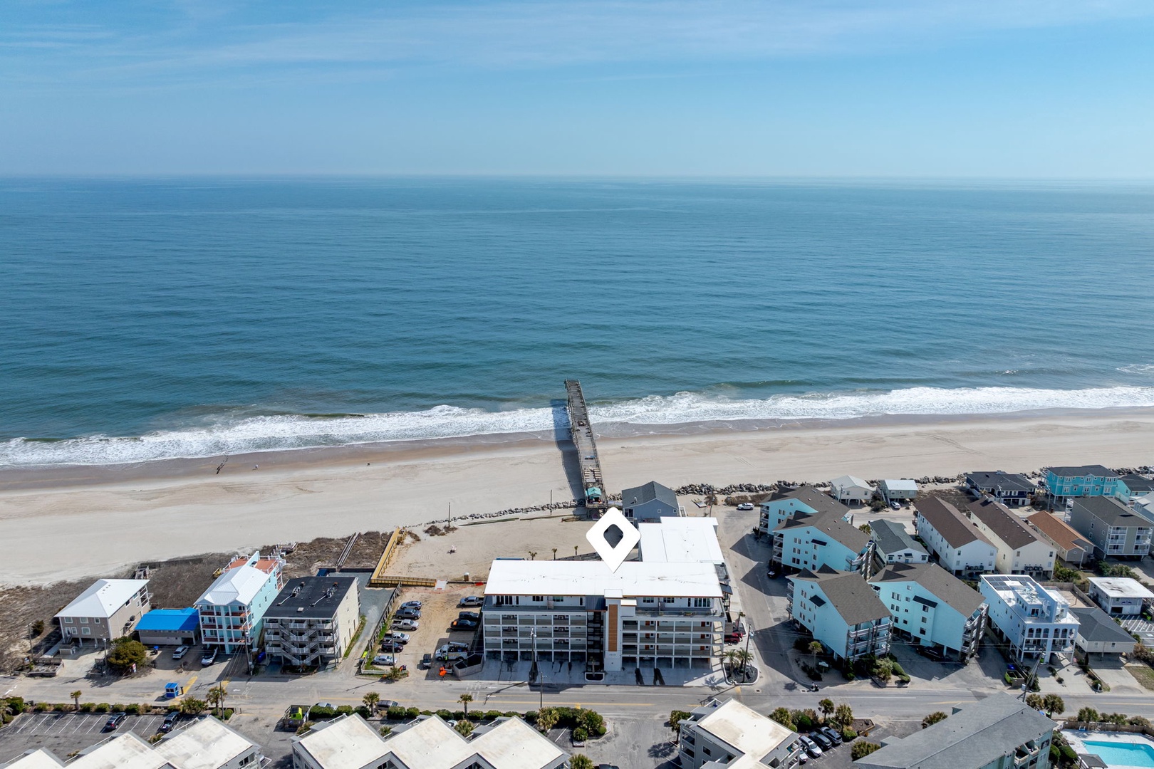 Stunning aerial view of beachfront property just steps from pristine sandy shores and rolling ocean waves.