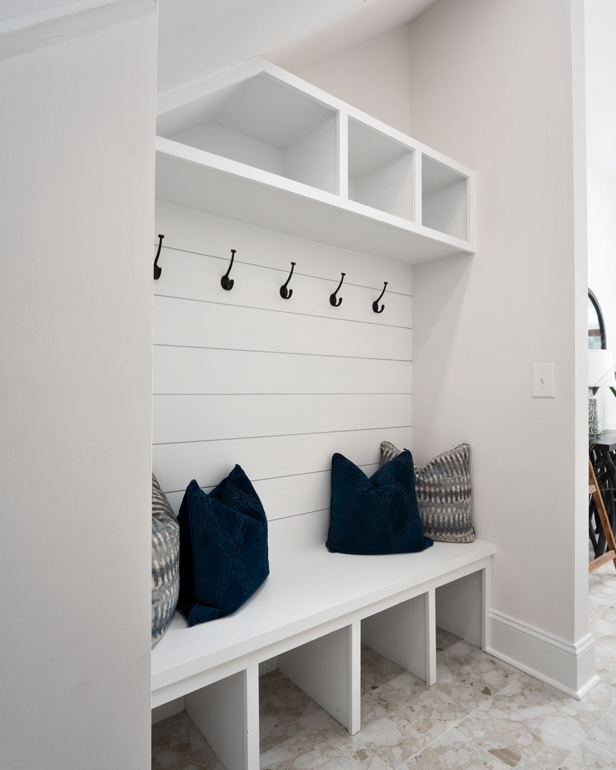 Your entryway welcomes you with built-in storage, cozy navy pillows, and hooks for easy organization after exploring.