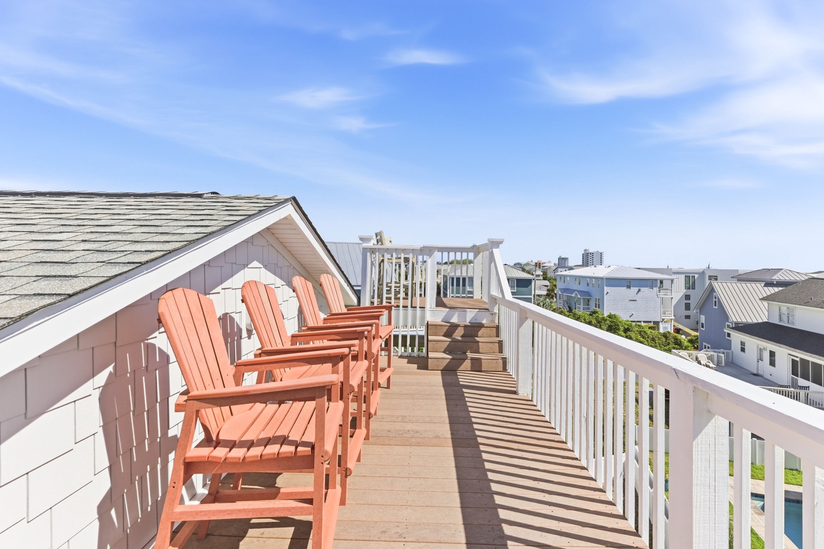 Rooftop terrace features coastal views across neighboring buildings, with Adirondack seating providing an elevated vantage point near the property's upper level.
