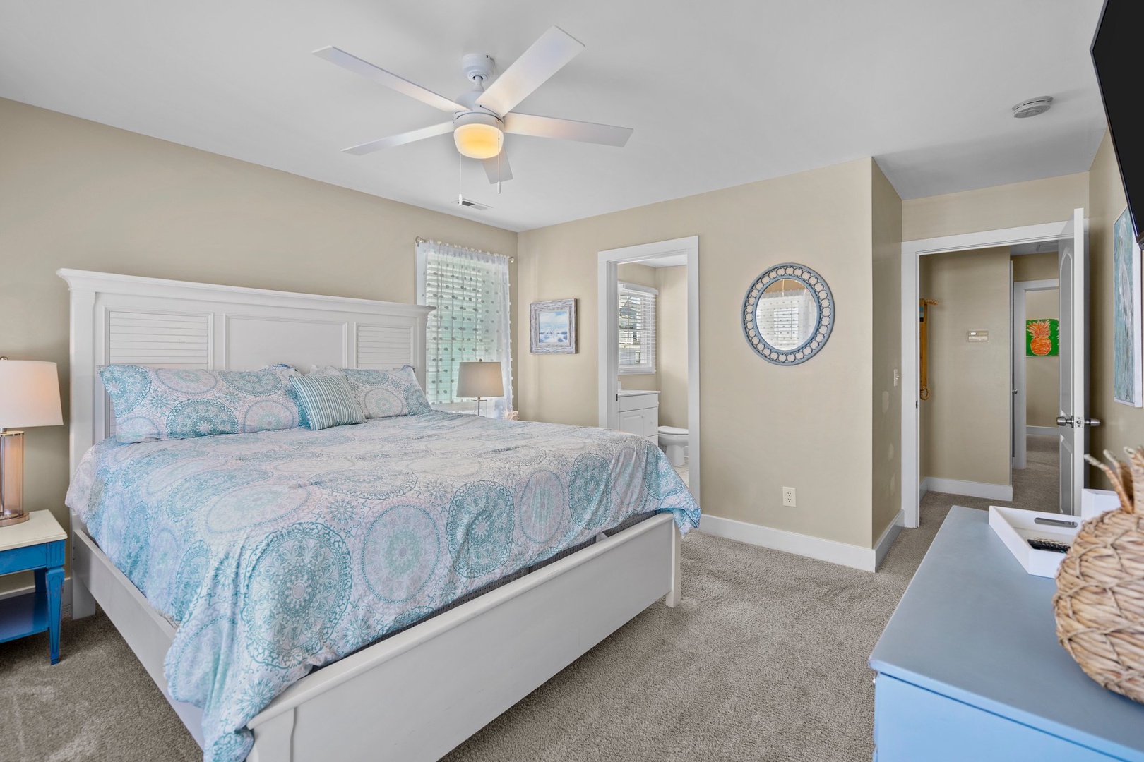 Drift off to sleep in your serene coastal-themed bedroom with soft linens, soothing colors, and gentle ceiling fan.