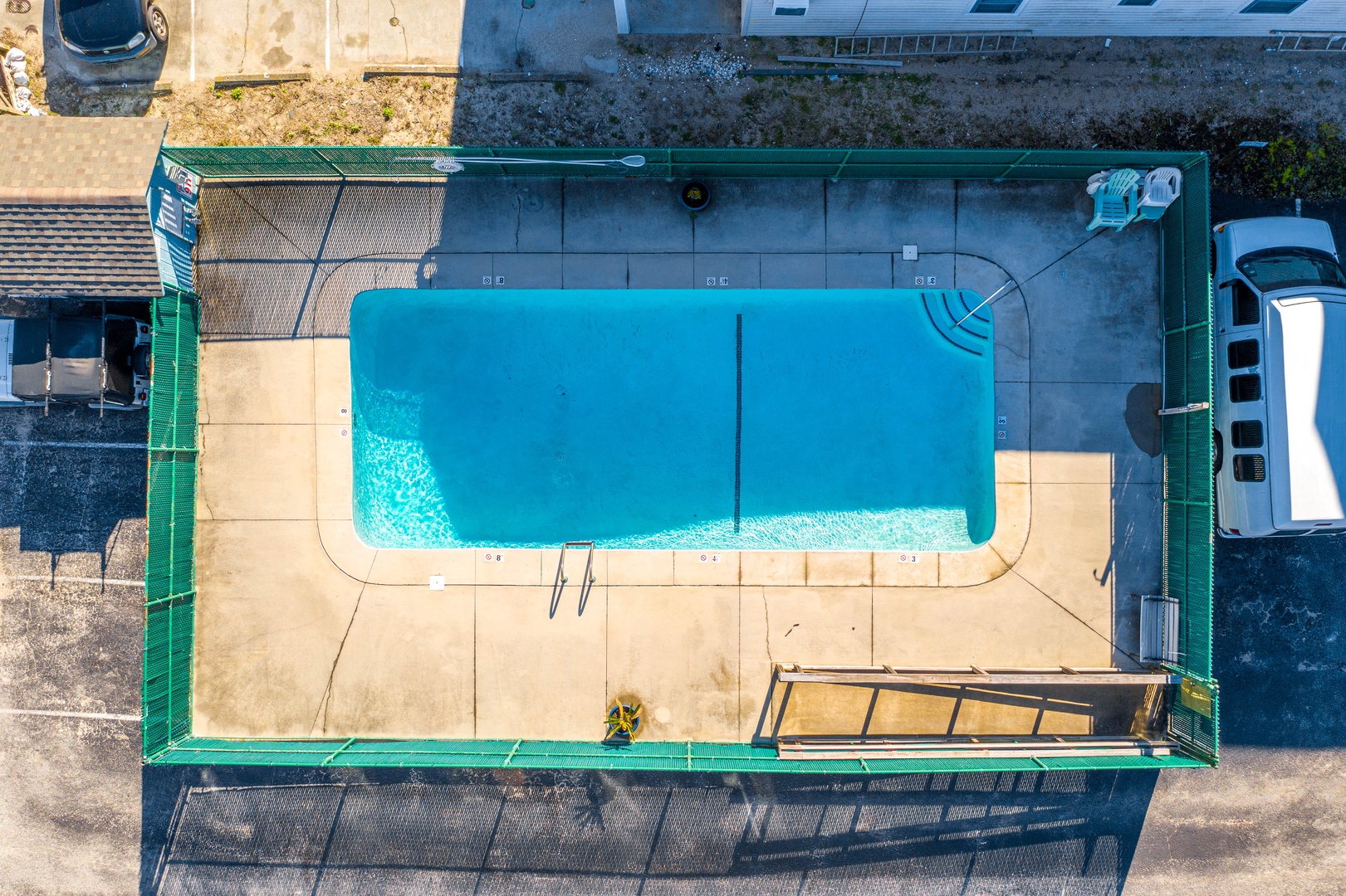 Aerial view of the property's rectangular swimming pool with surrounding deck area and safety fencing.