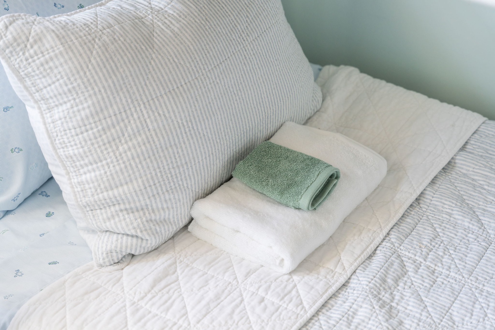 Fresh towels await you on crisp white linens, creating a welcoming bedroom retreat where comfort meets thoughtful details.