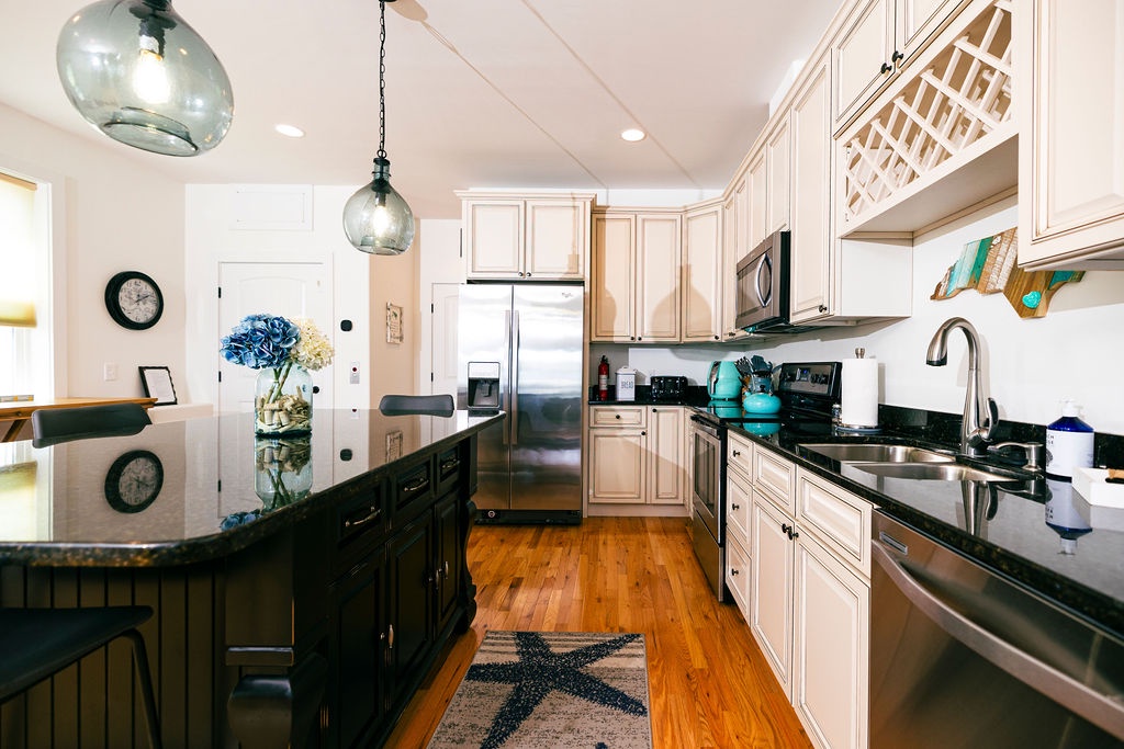 Your fully equipped kitchen awaits with sleek granite counters, stainless appliances, and coastal charm—perfect for preparing meals during your stay.