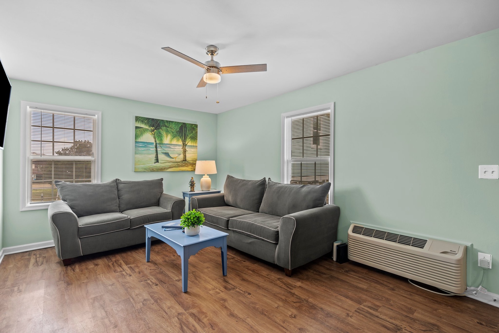 Relax in your coastal-themed living room with plush gray sofas and tropical artwork setting the perfect vacation mood.