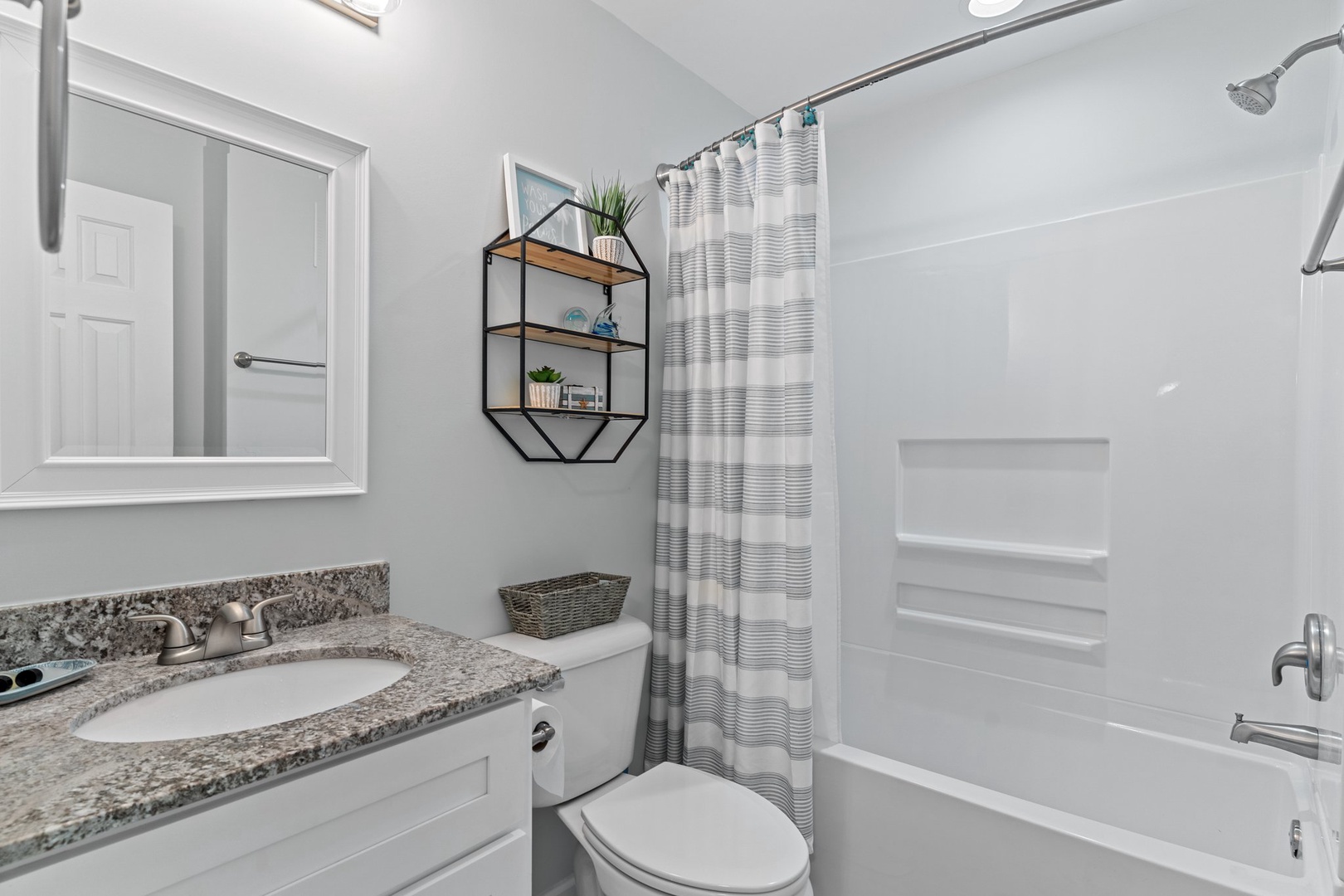 Your private bathroom features a granite vanity, spacious shower-tub combo, and thoughtful touches like floating shelves with plants.