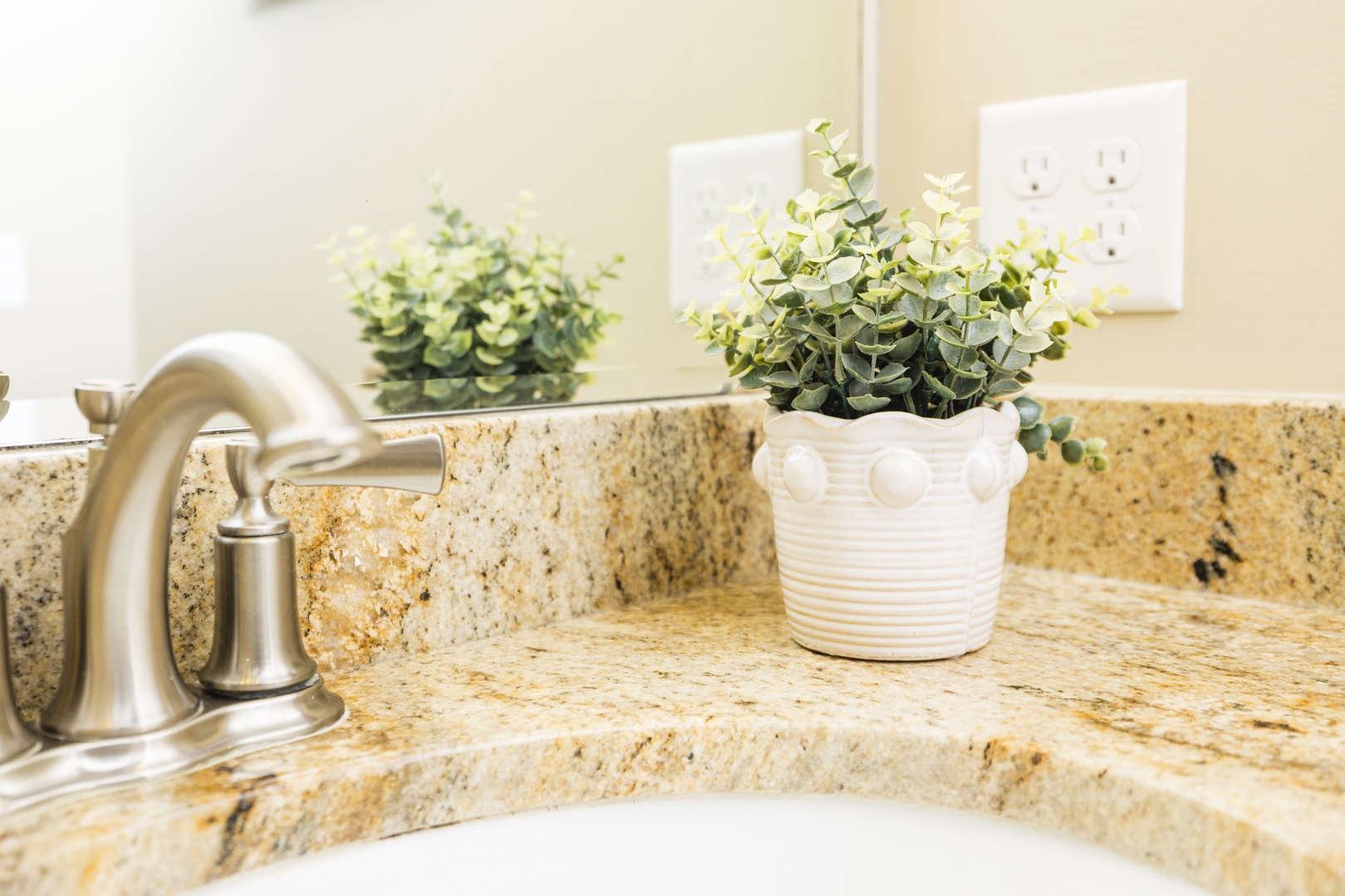 Refresh in your elegant bathroom featuring granite countertops, brushed nickel fixtures, and charming greenery that adds a spa-like touch to your morning routine.