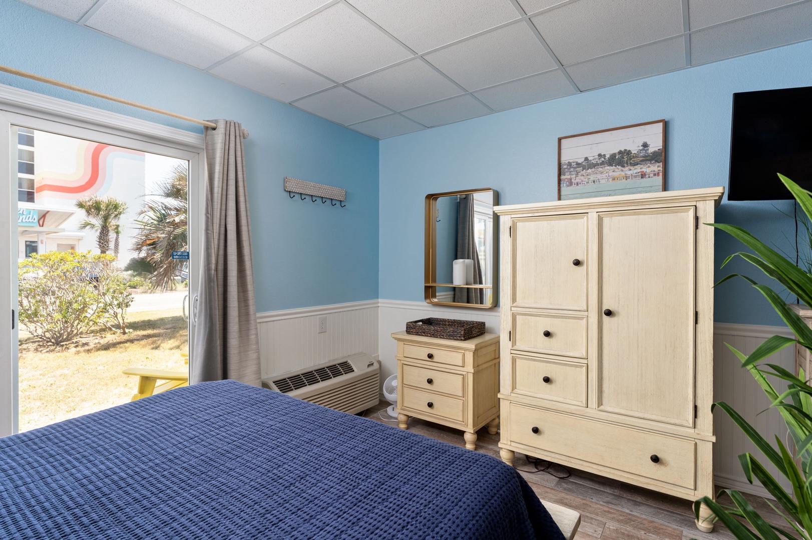 Drift off to sleep in this coastal-themed bedroom with bright blue walls, cozy nautical bedding, and charming white furniture that offers plenty of storage for your belongings.