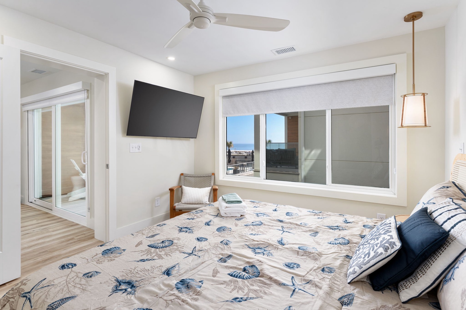 Wake up to ocean views from your comfortable king bed in this bright, airy bedroom with ceiling fan and wall-mounted TV for perfect relaxation.