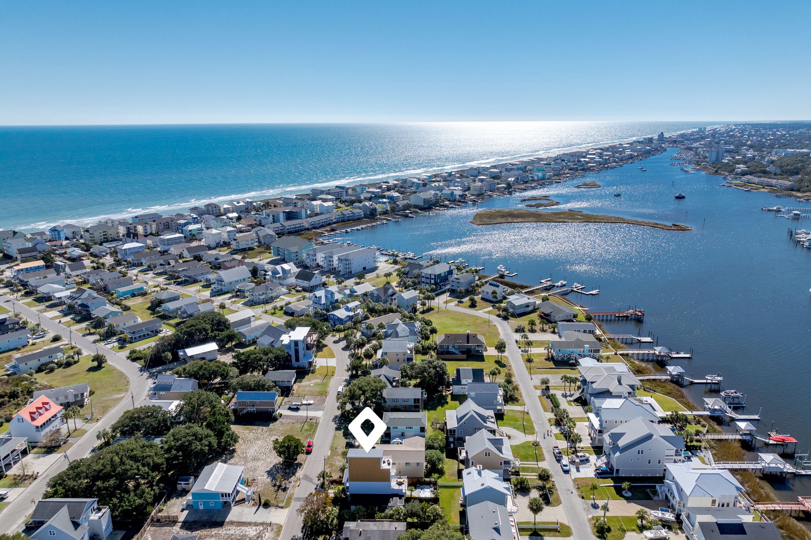 Aerial view of a charming coastal community with marina access, sandy beaches, and waterfront living just steps away.