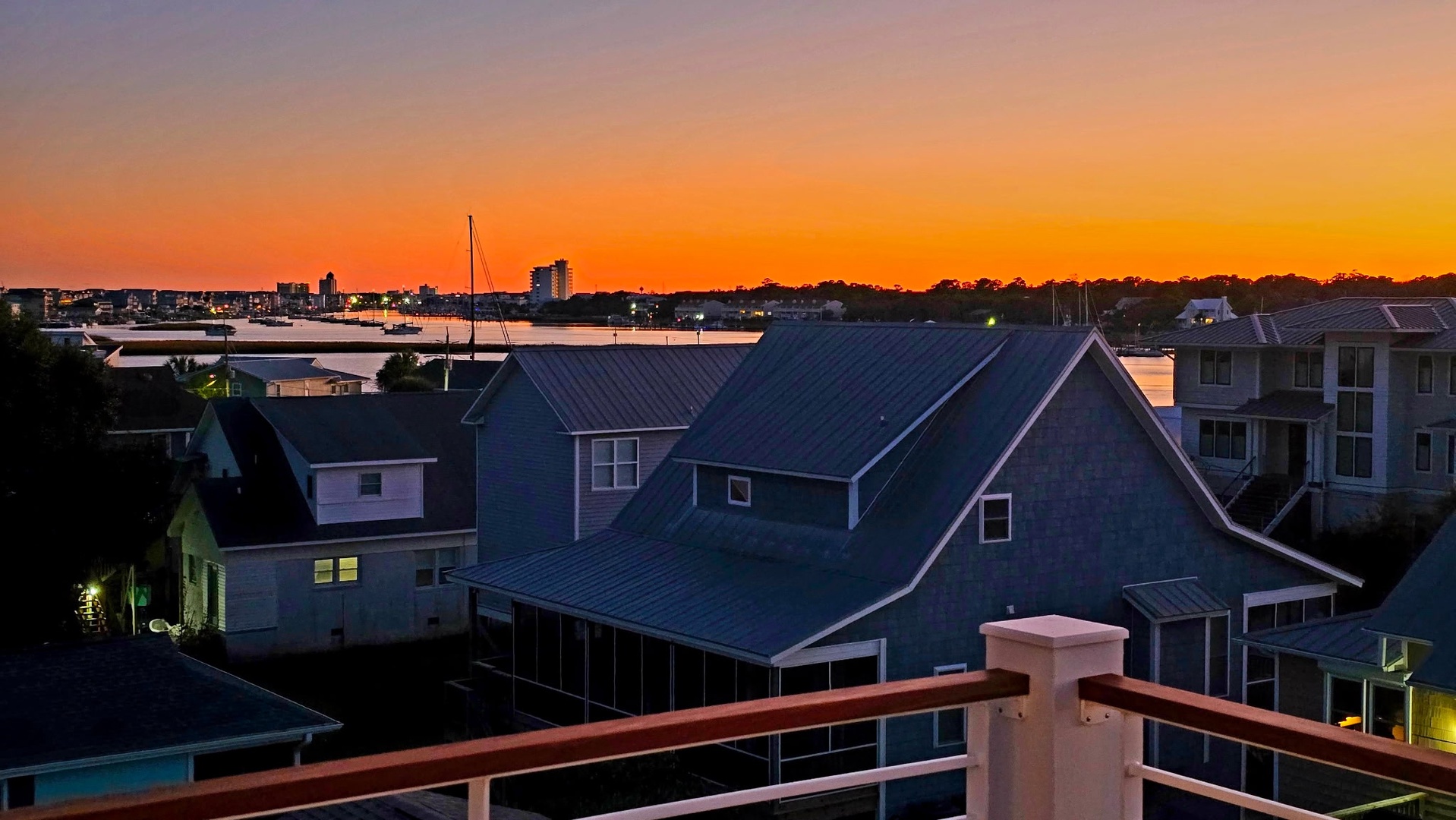 Stunning sunset paints the sky over this charming waterfront neighborhood with boats dotting the harbor.
