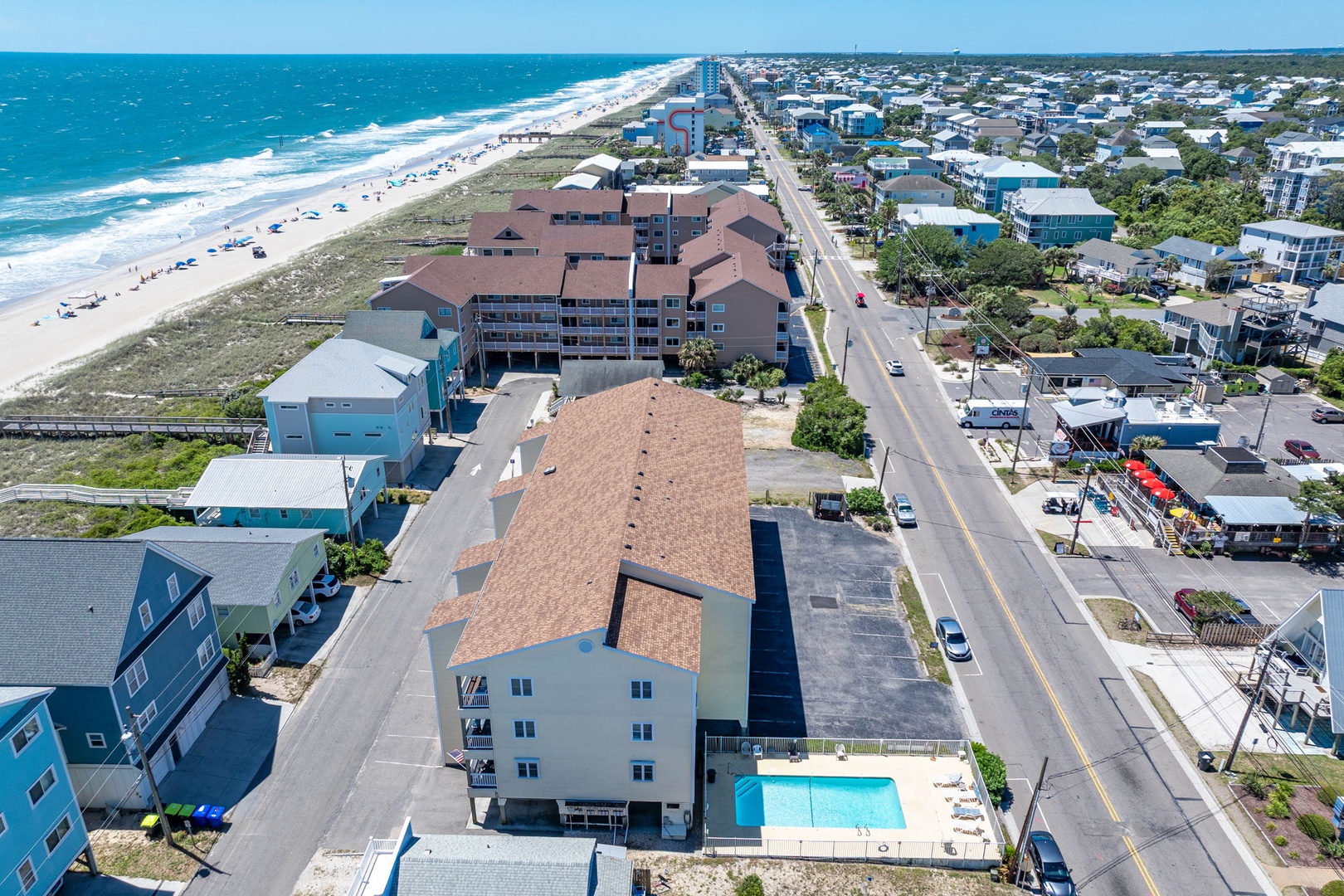 An aerial view reveals the property's prime beachfront location, with the ocean, sandy shores, and surrounding coastal community all within easy reach.