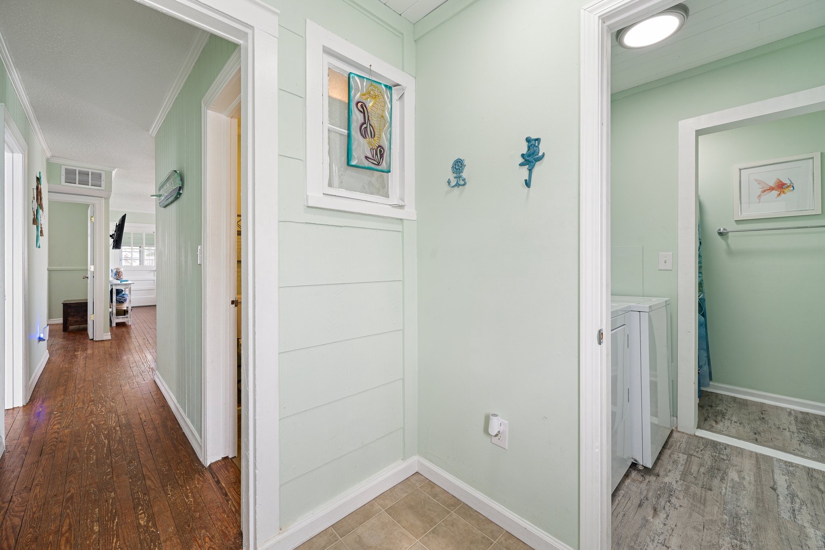 Relax in your coastal-themed hallway with charming seahorse decor, warm wood floors, and soothing mint walls connecting your peaceful retreat.