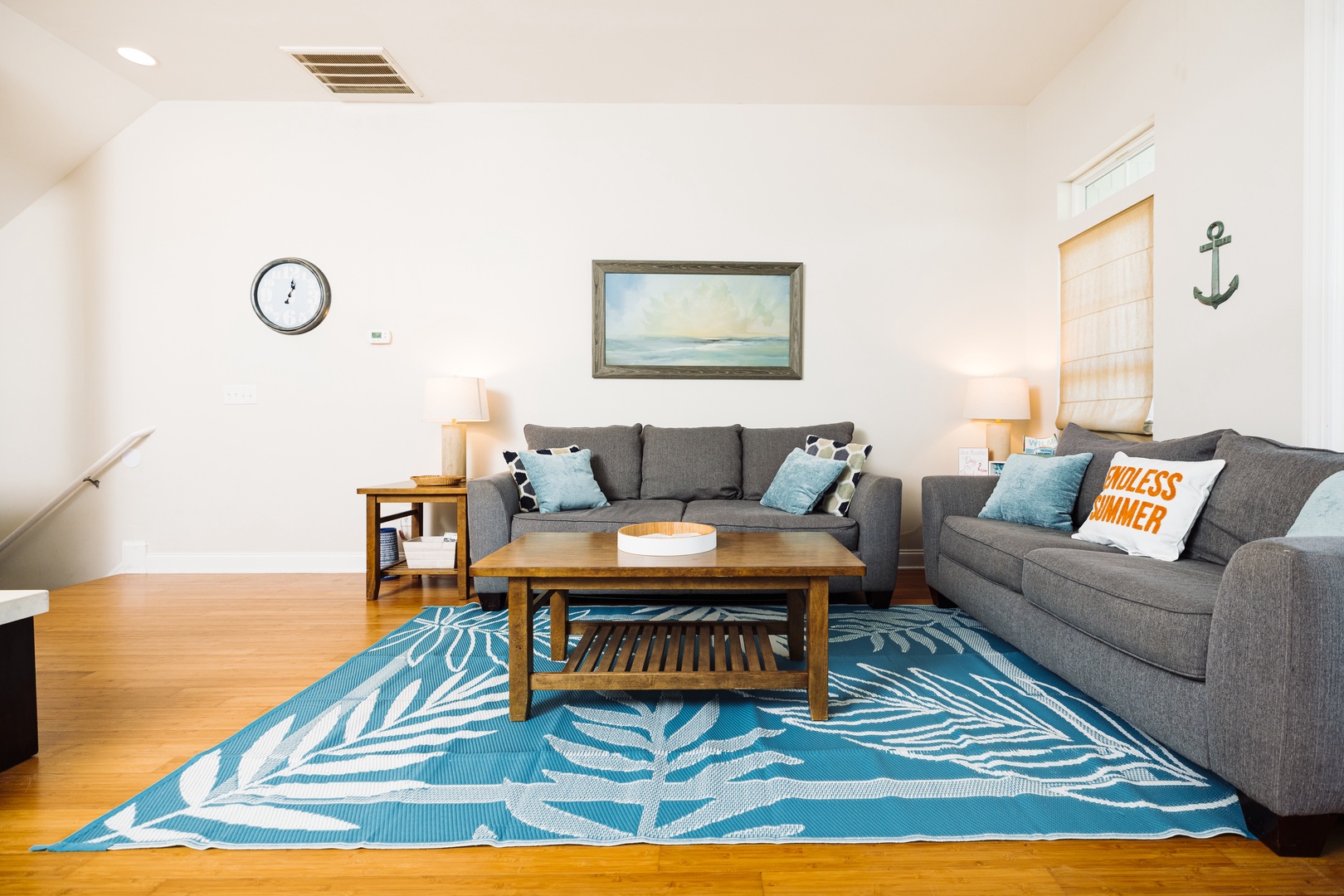 Unwind in your coastal-themed living room with plush gray sofas and cheerful blue accents that instantly put you in vacation mode.
