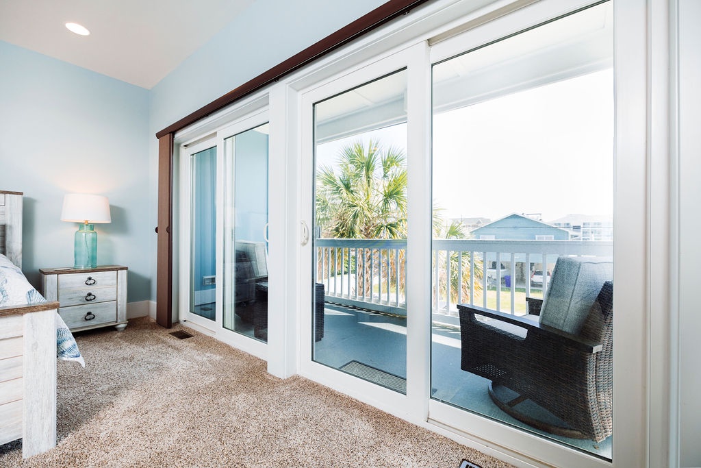 Wake up to coastal views from your serene bedroom, where sliding doors open to your private balcony overlooking palm trees and the neighborhood.