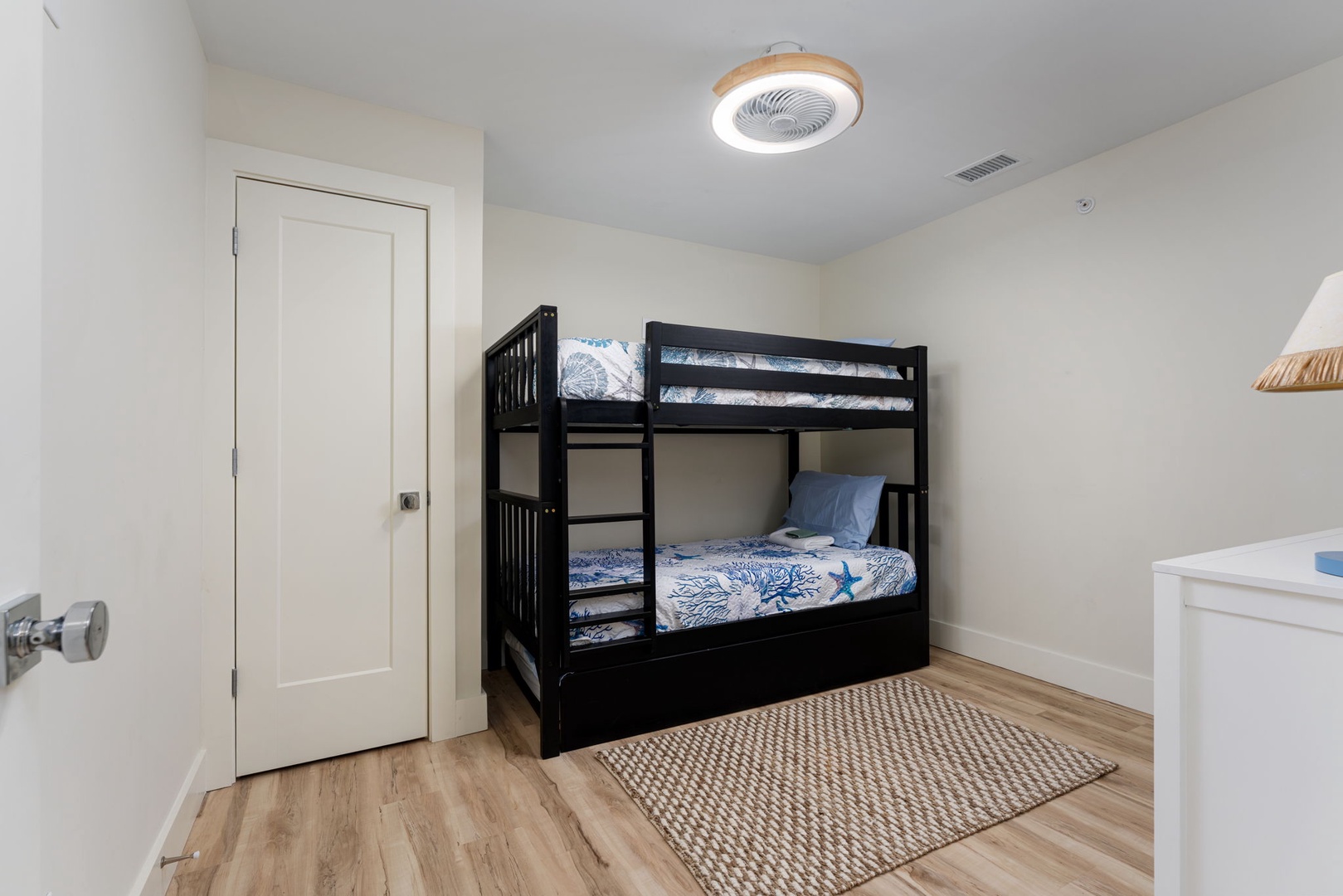 Your kids will love this cozy bunk bed setup, complete with ocean-themed bedding and a fun ceiling fan light combo overhead.