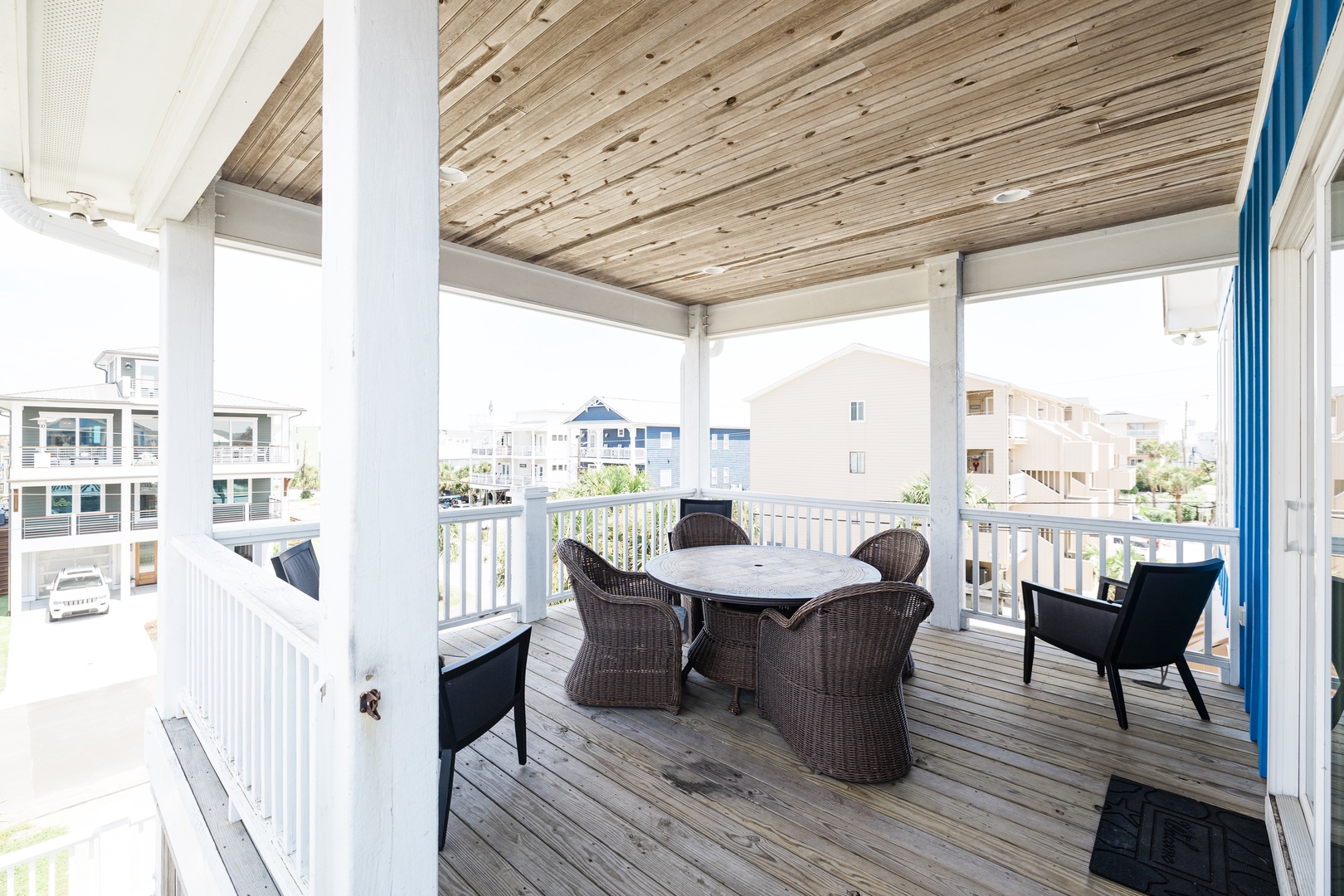 Your covered porch offers shaded comfort with wicker dining for six and relaxing chairs, perfect for morning coffee or sunset dining.