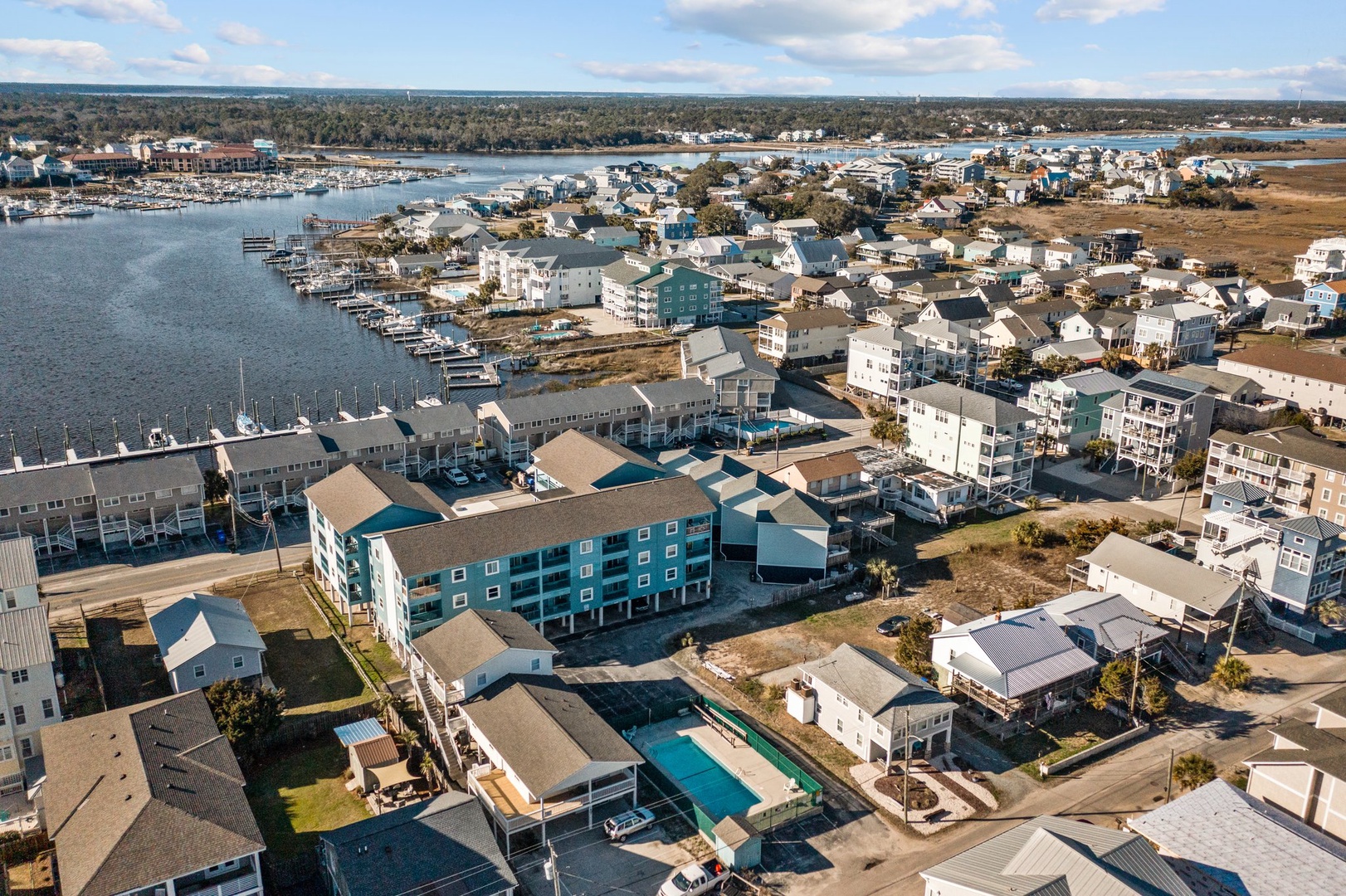 Aerial view of a charming coastal community featuring waterfront homes, marina, and swimming pools nestled along scenic harbors.