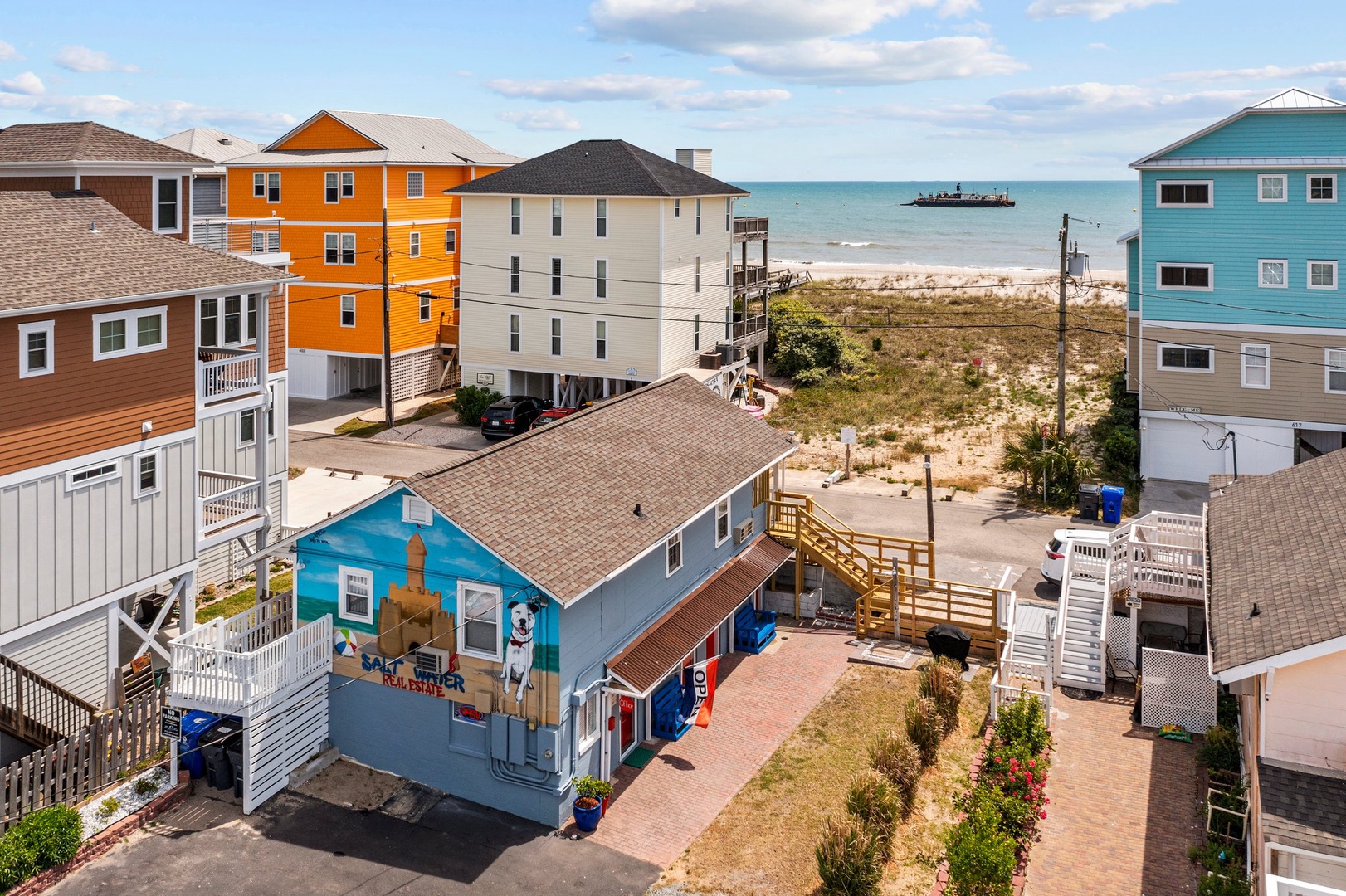Colorful beachfront homes create a vibrant coastal community just steps from sandy shores and ocean waves.