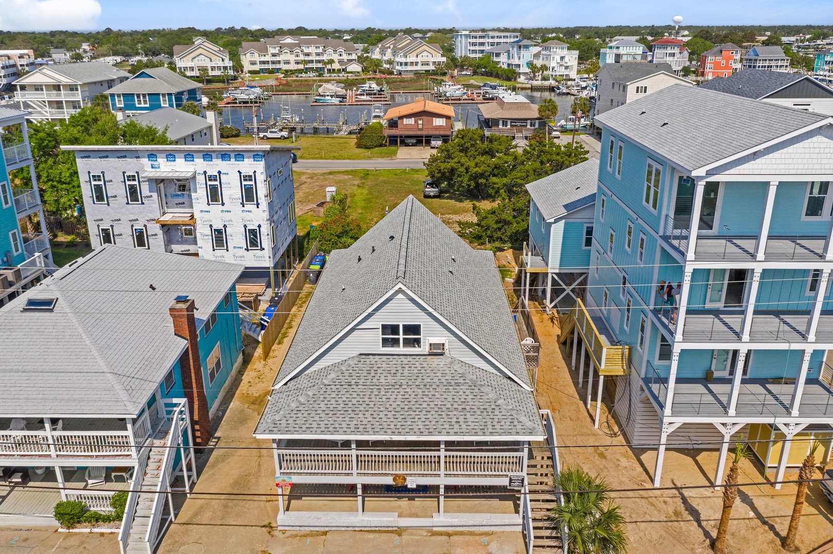 Aerial view of a charming beach neighborhood featuring colorful coastal homes and nearby marina access.