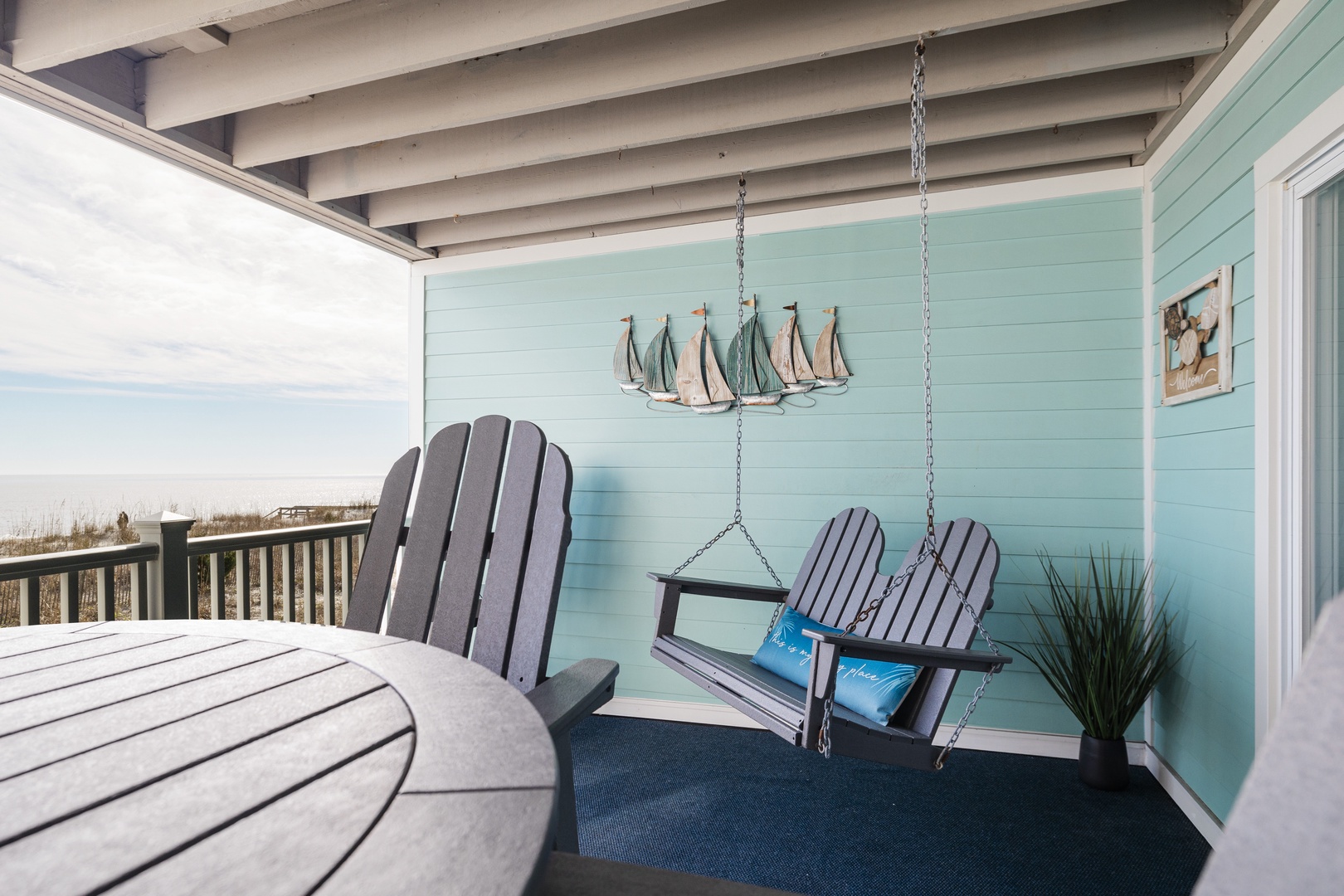 Your private coastal retreat awaits with Adirondack chairs, charming swing, and nautical touches overlooking serene beach views.